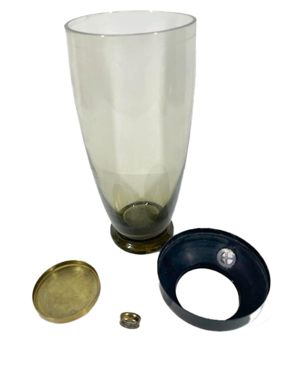 Art Deco, olive green glass footed cocktail shaker with a black enameled steel lid having a brass cover and screw-on spout cap.