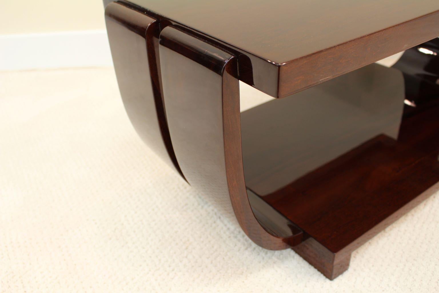 Professionally restored Machine Age cocktail table by the Modern Age Furniture Company. Stylized with double banded curved sides and finished in a rich walnut gloss finish. Measures: Height 16, length 34 1/2, width 17.

Reference: American Art