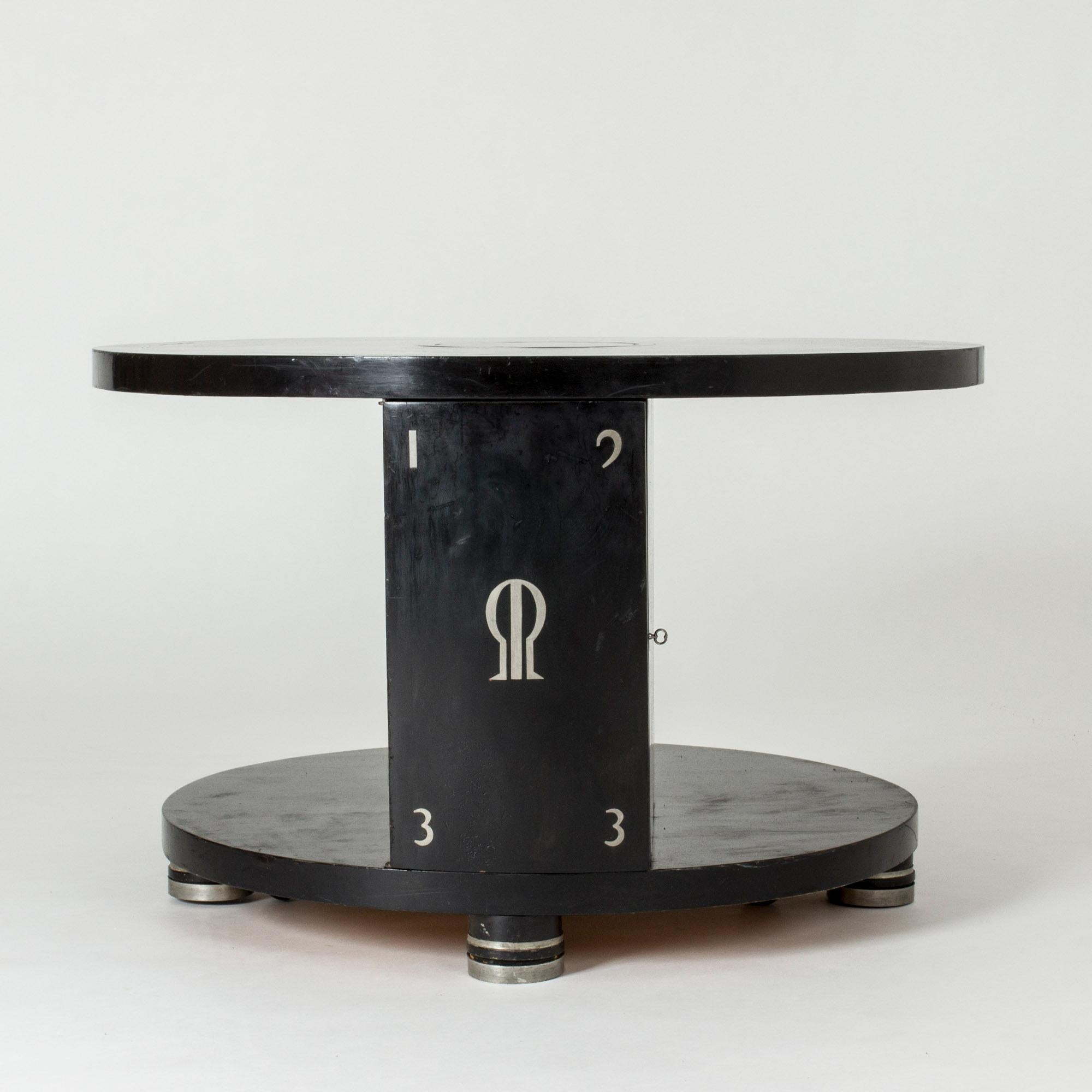 Art Deco coffee table by Alvar Andersson, made from black lacquered wood with pewter inlays and feet. Wheels allow the table to slide if it needs to be moved. A small cabinet is built into the table, with two shelves.