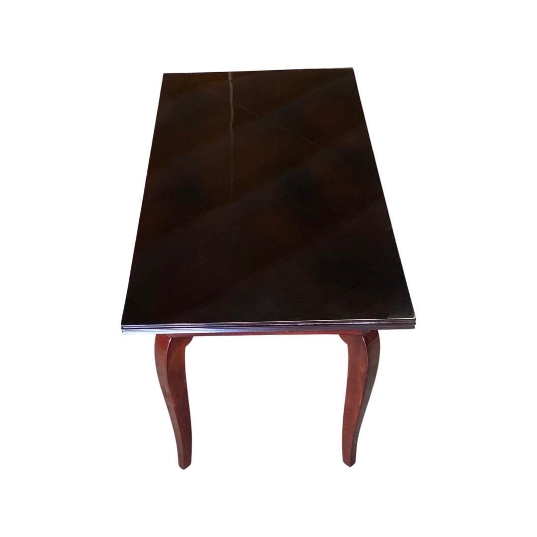 A  rectangular coffee table made from Rosewood with a Black lacquered top.  The 4-rounded legs of this table make it a classic design of the Art Deco period.  This table was made in France and was designed by Jules Leleu in collaboration with famous