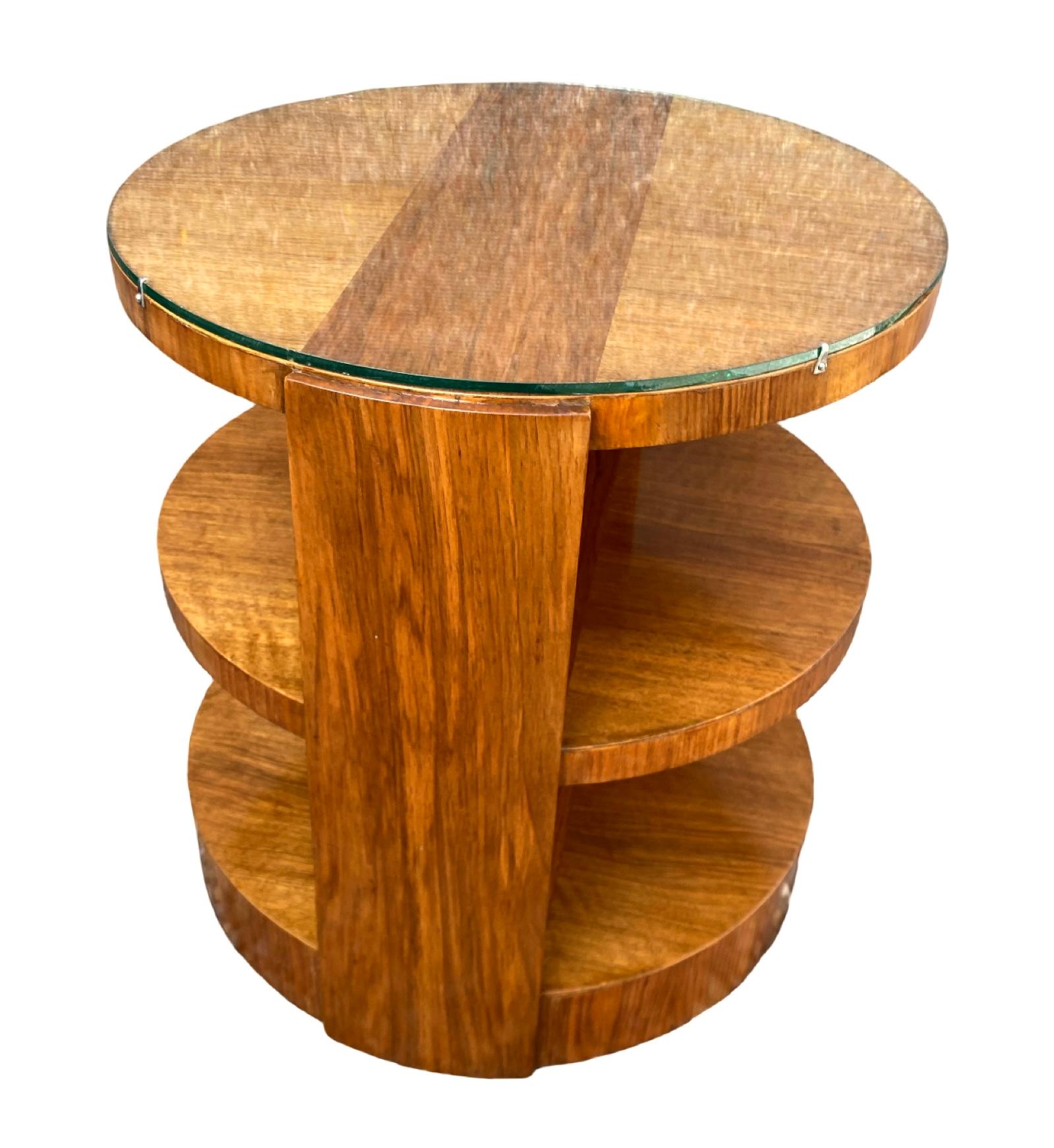 A beautiful Art Deco Coffee table in a lovely mellow walnut. The circular top has a darker walnut inset panel down its centre, which is repeated on the 2 lower tiers also. The protective glass top clips in place neatly via small chrome clips. The