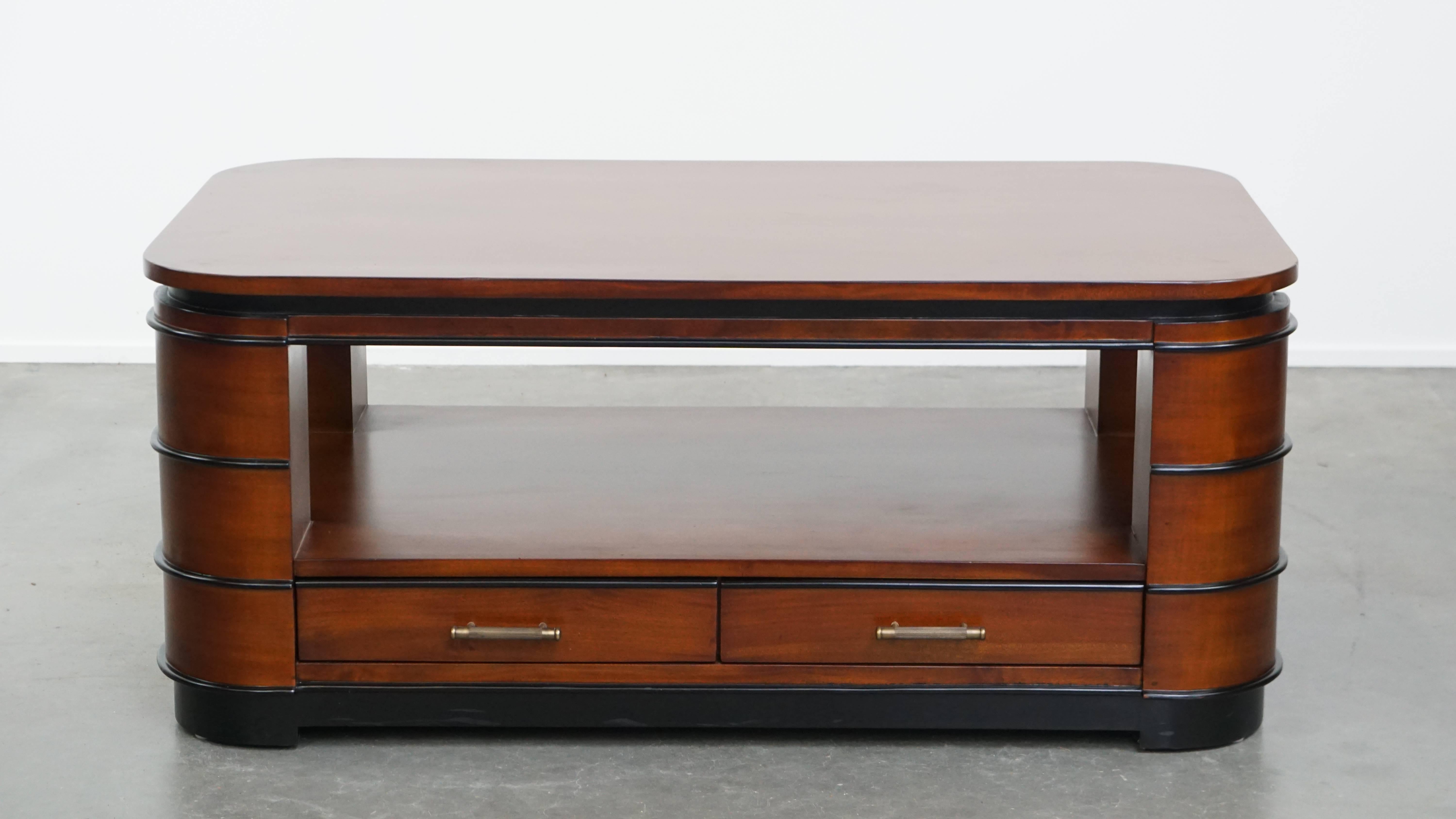 Offered here is this beautiful Art Deco design coffee table made of mahogany, featuring four drawers and an open space beneath the tabletop. This stunning piece fits effortlessly into nearly any interior, thanks to its timeless elegance and clean