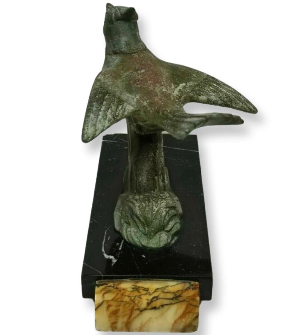 An Art Deco cold painted bronze figure of a bird sitting on a branch, beautiful detail, the bird singing with open beak and wings spread almost as if it is ready to fly from the well defined branch it is standing on. The bird has lovely patination