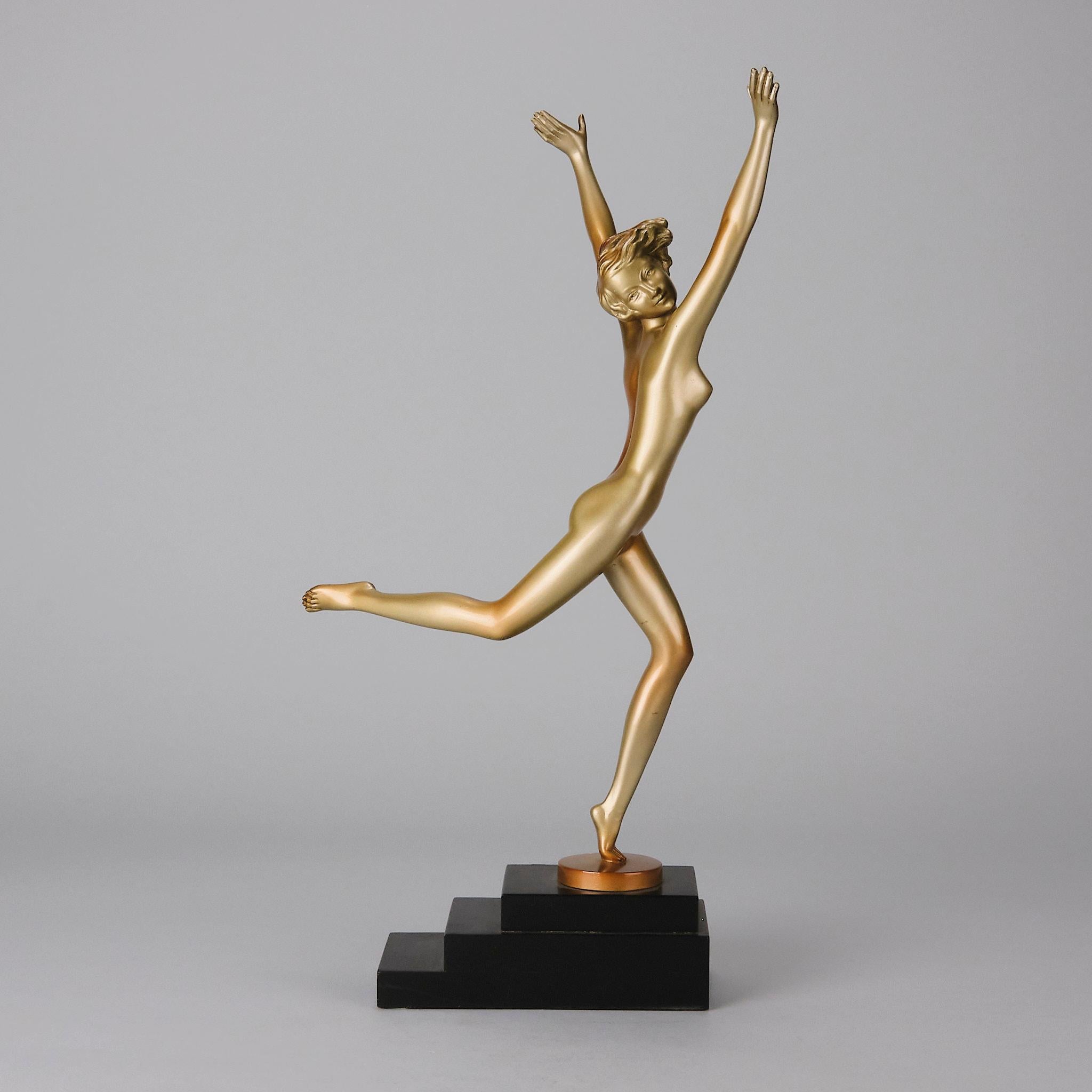 An attractive early 20th Century Art Deco cold painted bronze figure of a naked dancer with her arms raised high in an elegant pose with her rear leg raised. The sculpture exhibits excellent colour and very fine hand finished surface detail, raised