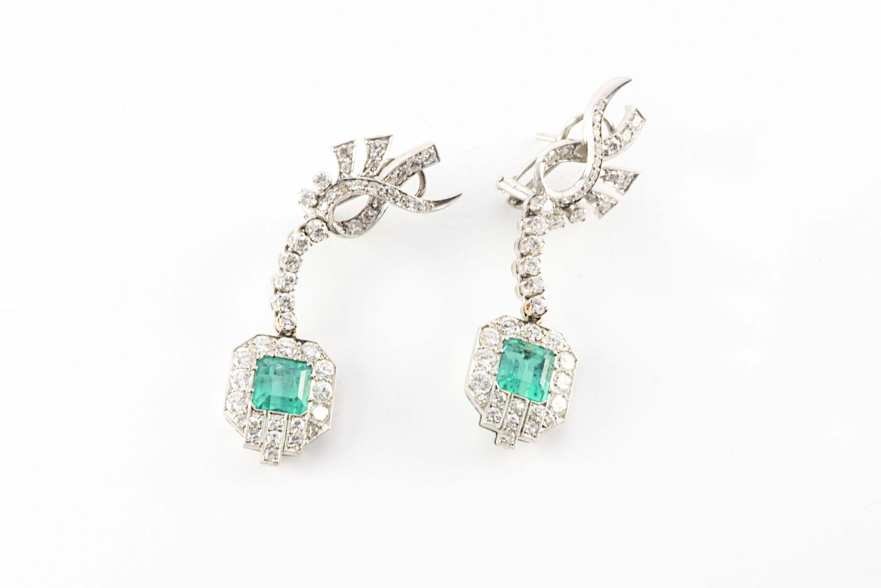 A mix of icy white single cut and Old European cut diamonds, G-H color, VS-SI clarity, totaling approximately 2.00 carats adorn these dazzling Art Deco drop down earrings designed around two square-shaped emerald-cut vibrant green Colombian emeralds