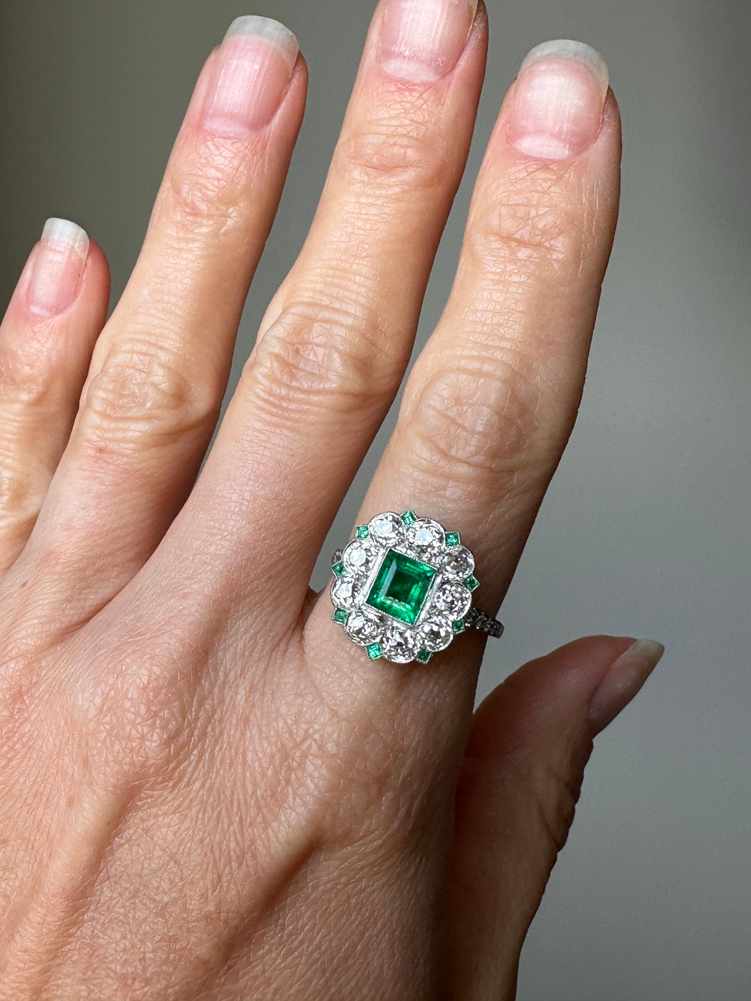 This ravishing Art Deco dinner ring centers on a richly saturated rectangular step-cut Colombian emerald that glows from within 2.3 carats of chunky old mine-cut diamonds interspersed by teeny tiny square step-cut emeralds set in platinum. This ring