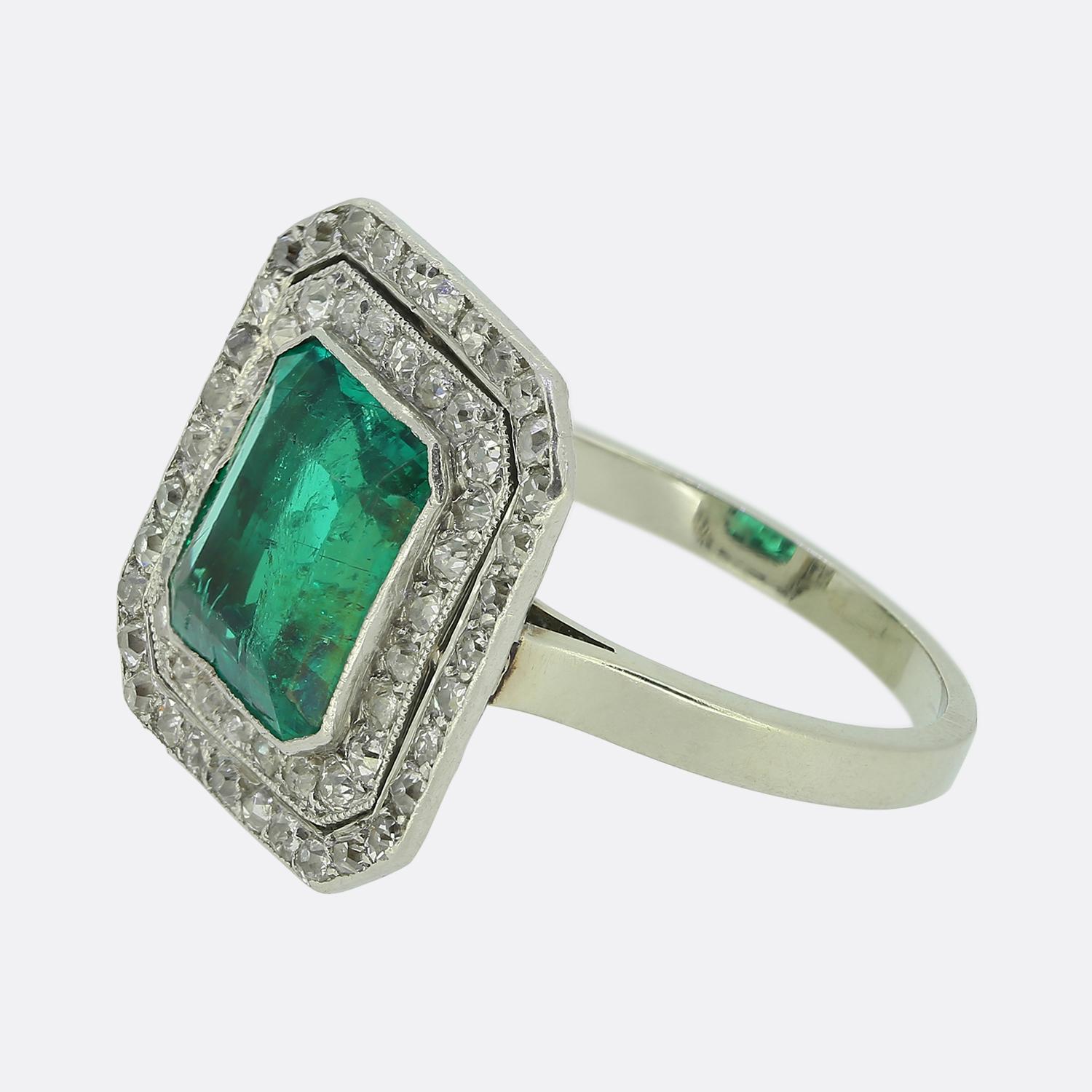 Nous avons ici une exquise bague à grappes réalisée en platine à l'époque où le style Art déco était à la pointe du design mondial. Au centre du visage, une émeraude d'origine colombienne, d'un vert éclatant, est légèrement surélevée. Autour de