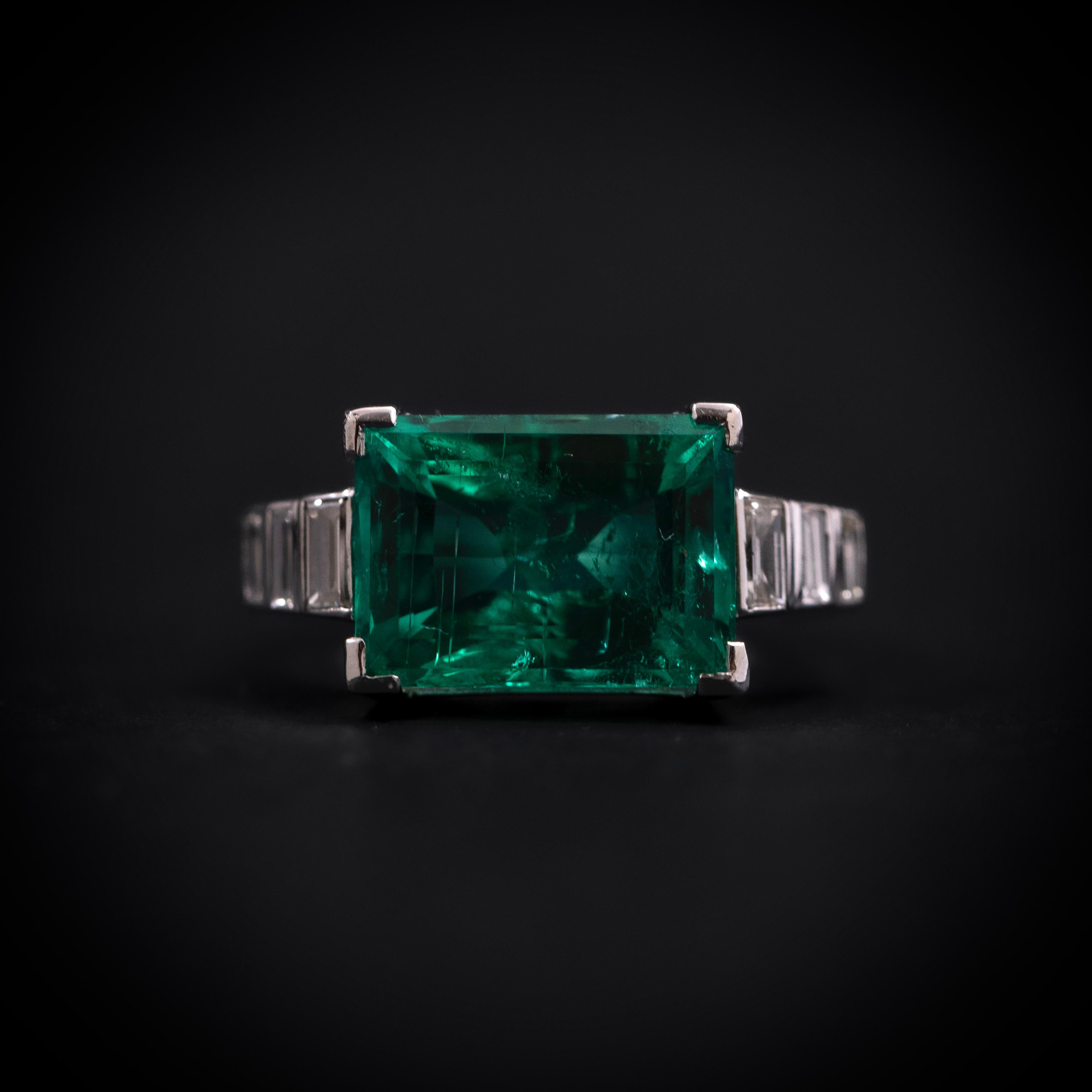 Art Deco Certified Colombian Emerald and Diamond Engagement or Cocktail Ring in Platinum, 1930s.

A stunning example of 1930s Art Deco elegance, this ring features a vibrant, deep green baguette-cut Colombian emerald weighing 5.25 carats, securely