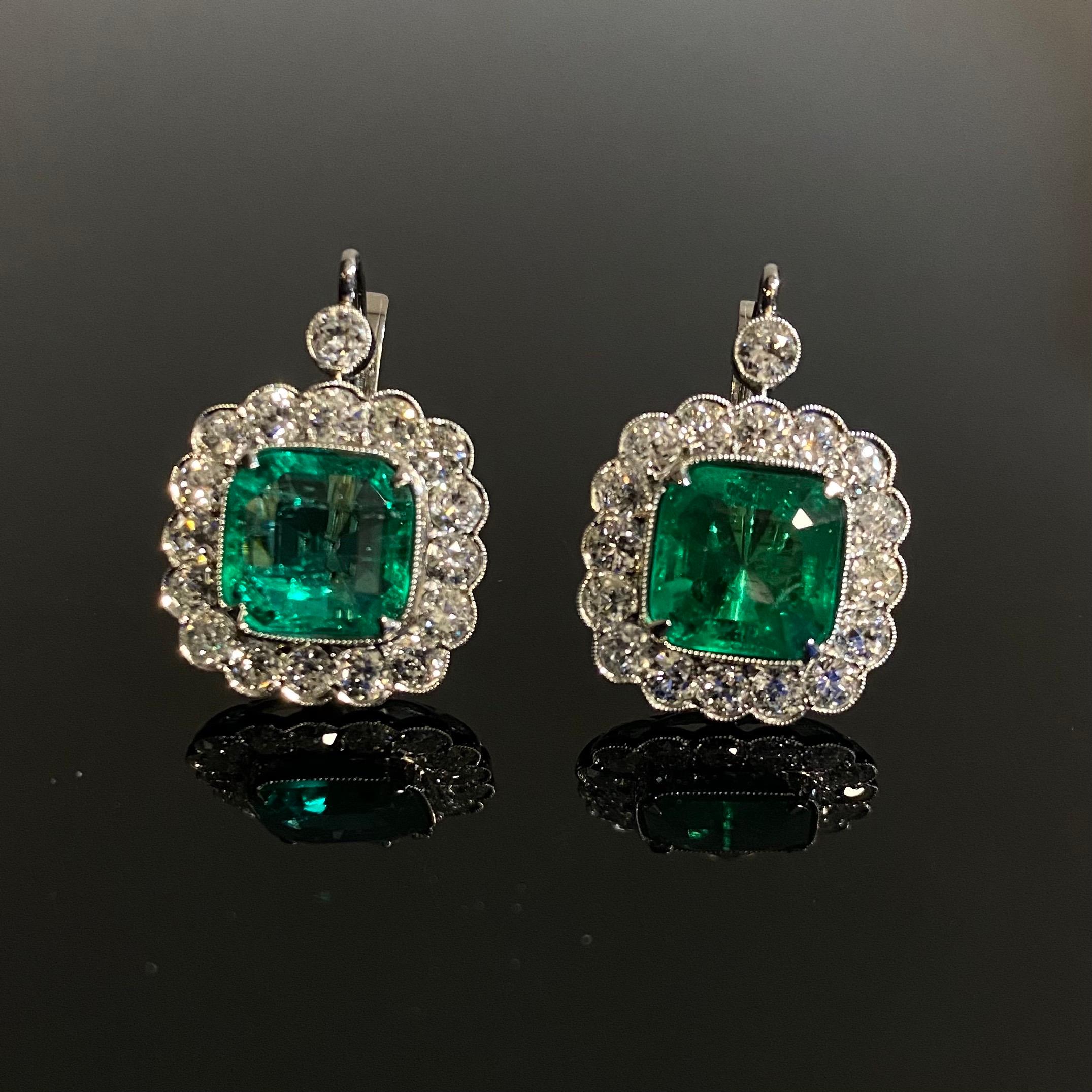 A pair of 20th Century Colombian Emerald and Old Cut Diamond Cluster Lever-Back Earrings in Platinum, Portuguese, Signed, made circa 1916-1972. Each earring designed in the Art Deco fashion is claw-set to the centre with a square emerald-cut emerald