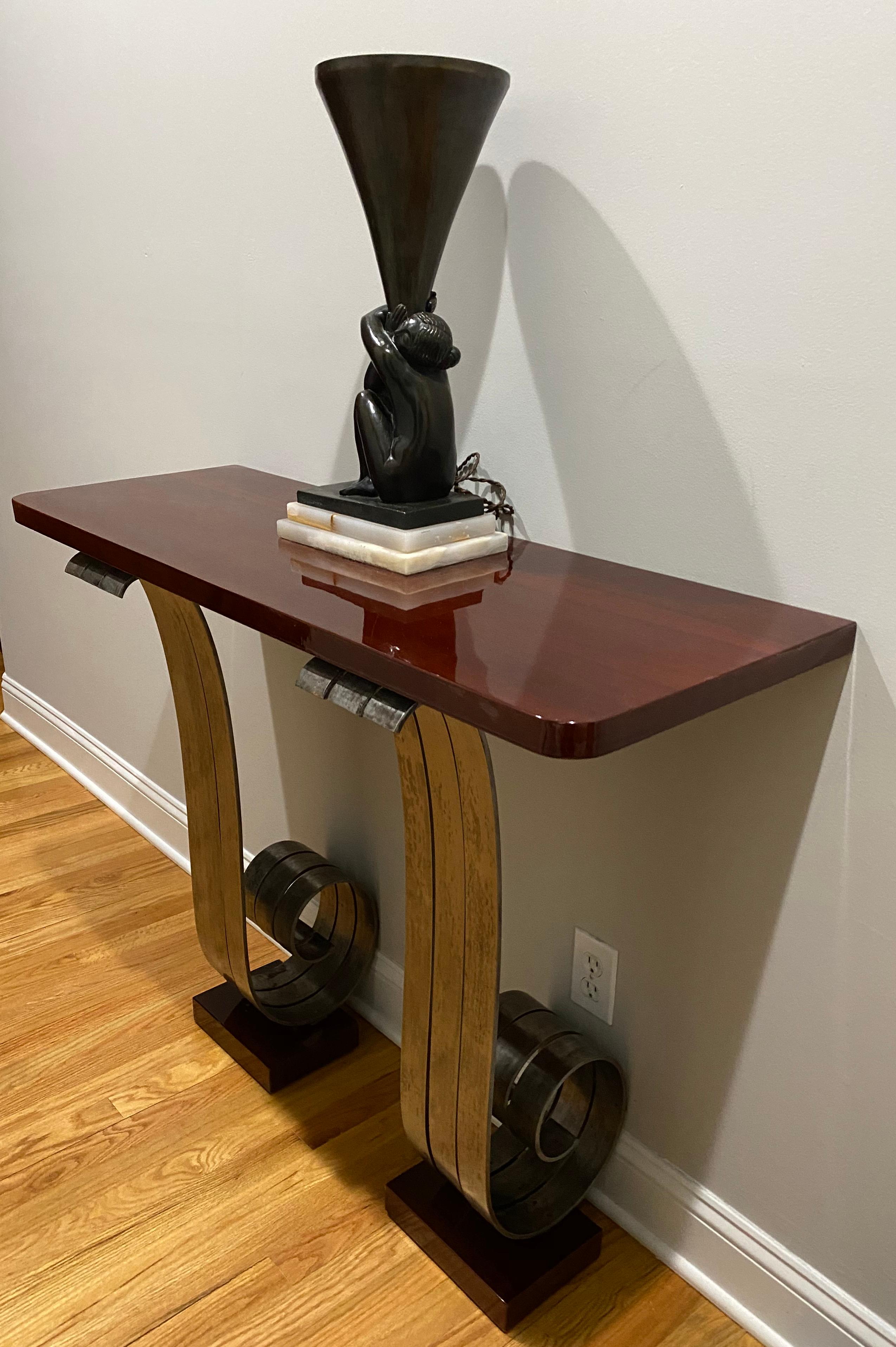 French Art Deco style console standing on two iron scrolled legs in the manner of Raymond Subes, with lacquered wood top and feet. Measures: Width 43