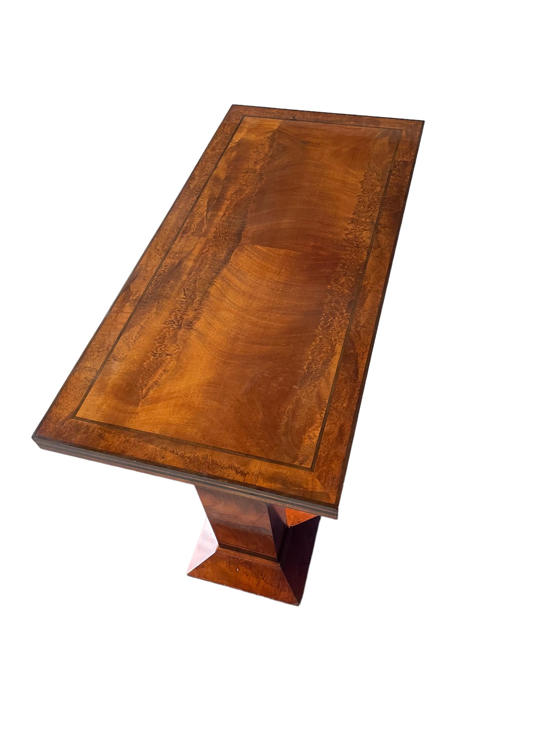 A fine Console/Serving table by Charles A Richter for Bath Cabinet Makers. In figured mahogany, with ebony banding. The rectangular top, supported by rectangular pedestals, with angled feet and a central shelf.
The matching sideboard also available