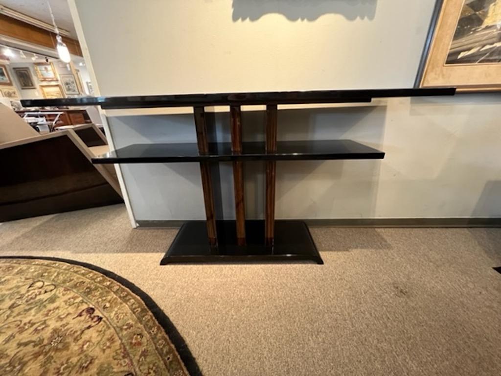 Beautiful console is made out of 2 different size shelves, connected with 3 wood supporters, attacher to trapezoid stable base. 
Console made out of Macassar wood, 2 shelves and base are ebonized, which create wood grain juxtaposition between