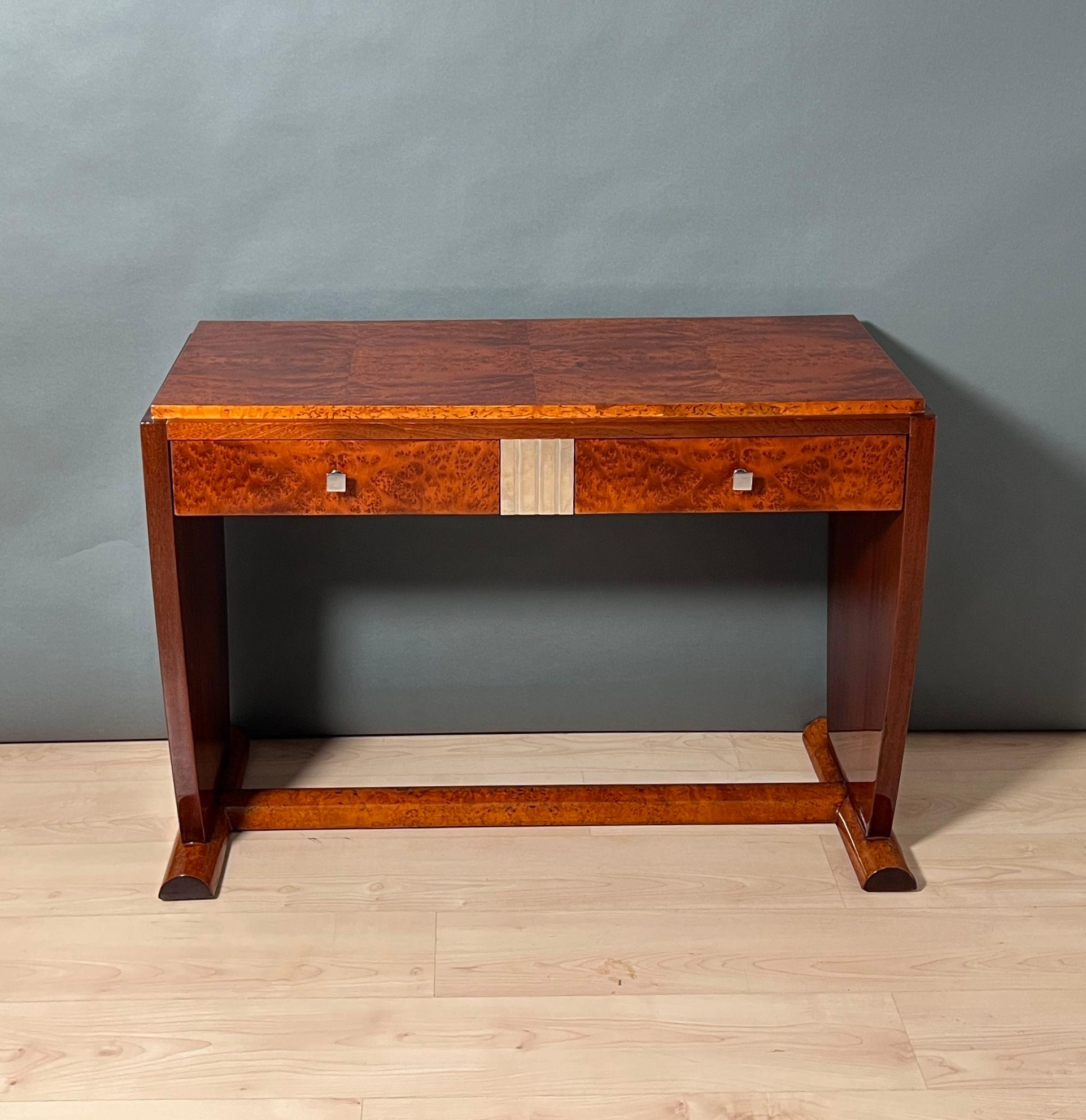 Elegant Art Deco console table or coiffeuse from France around 1925.
Thuja burl, polar birch and mahogany wood. Central ornament with silver leaf. 2 drawers with angled knobs at the top, mahogany wood inside. Completely restored with clear piano