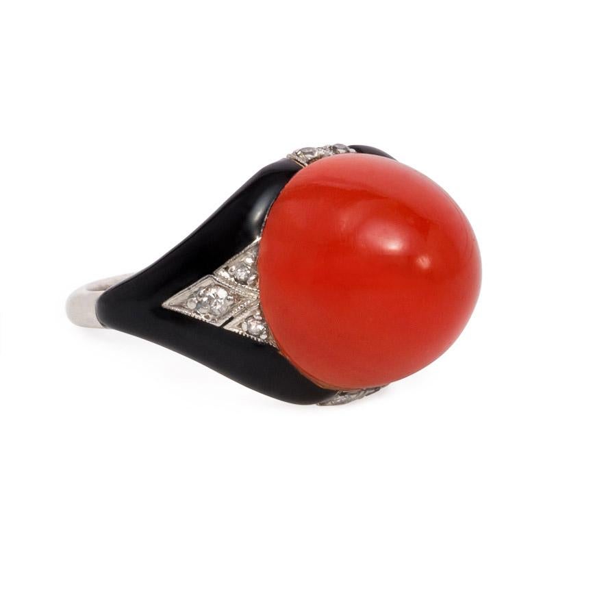 An Art Deco coral, enamel, and diamond ring in platinum and 14k gold.  The vibrant red-orange of the sugarloaf coral cabochon pops against a black enamel, diamond, and platinum mounting that serves as the perfect foil for this flame-colored gem. 
