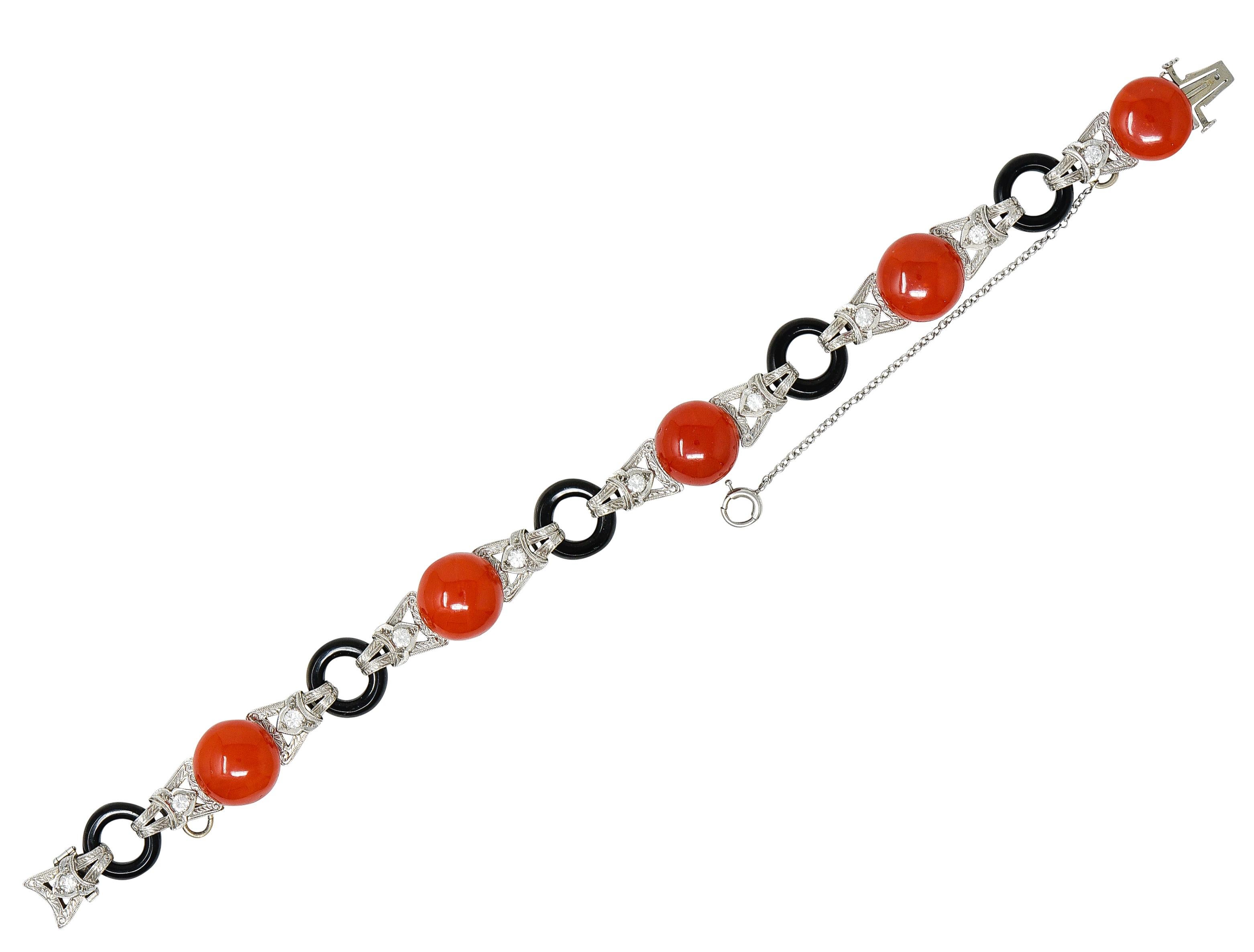 Link bracelet features button cabochon coral alternating with donut ring onyx. Coral are opaque and uniformly orangey red in color while measuring approximately 11.0 mm. Onyx are opaque black with good to very good polish while measuring