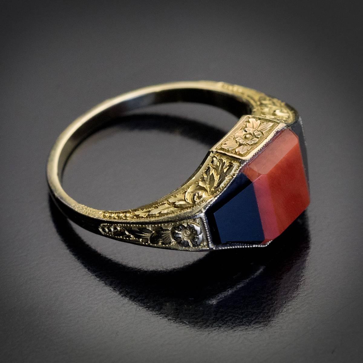 Austria, Vienna, circa 1930

A vintage yellow 14K gold unisex ring with finely hand-carved floral designs is centered with a rectangular natural coral flanked by two trapezoid shaped black onyxes (a variety of agate).

The ring is marked with