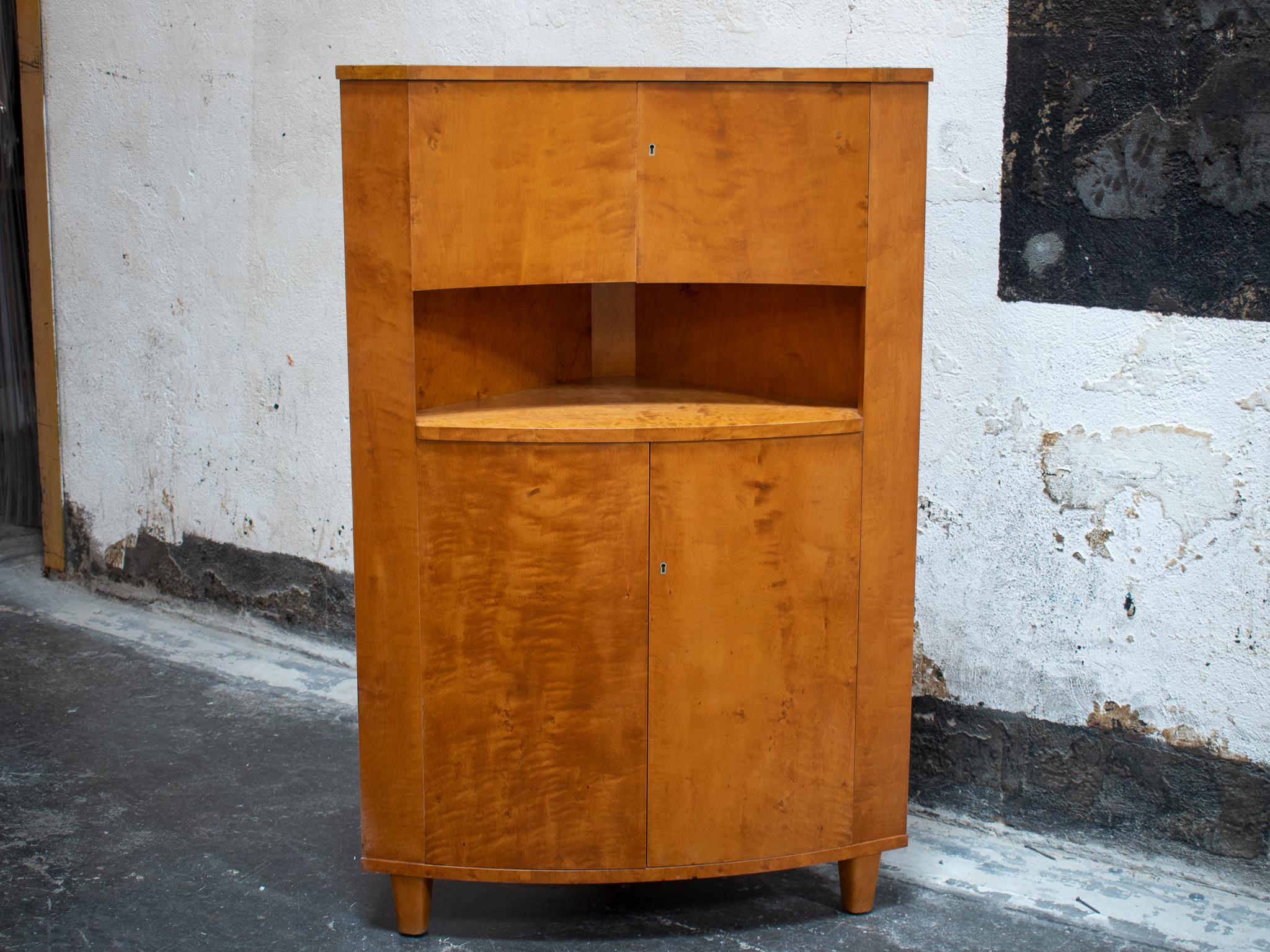 Unique Art Deco corner cupboard made of Swedish Flame Birch. Could also work very well as a bar. Features upper and lower cabinets and an exposed shelf. The bottom cabinet is curved convexly and the upper cabinet is concave.