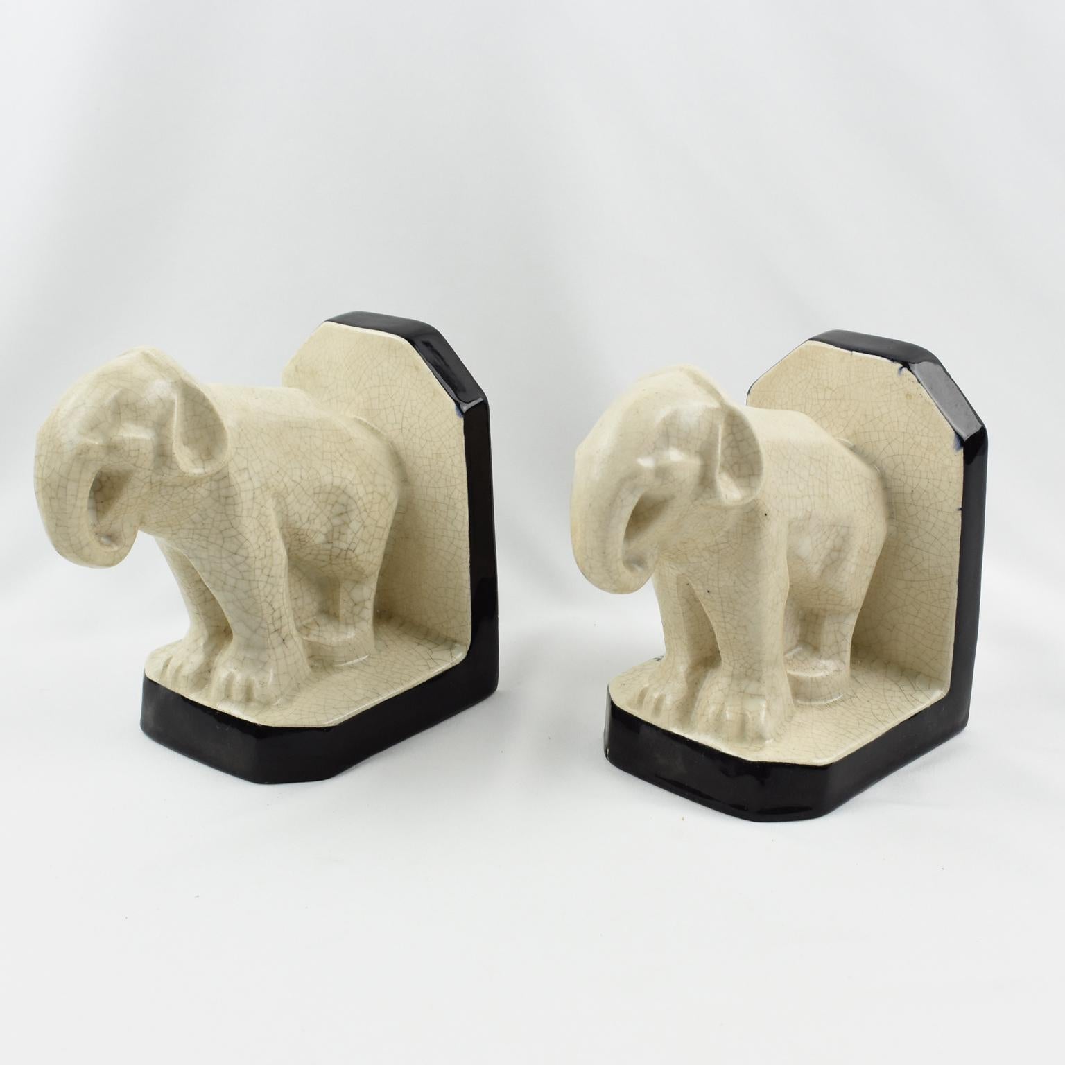 This superb Art Deco pair of crackled ceramic bookends was designed and crafted by Le Moine, France, in the 1930s. The off-white colored crackle glaze ceramic or faience sculpture features a pair of elephants with contrasted black enameled glaze