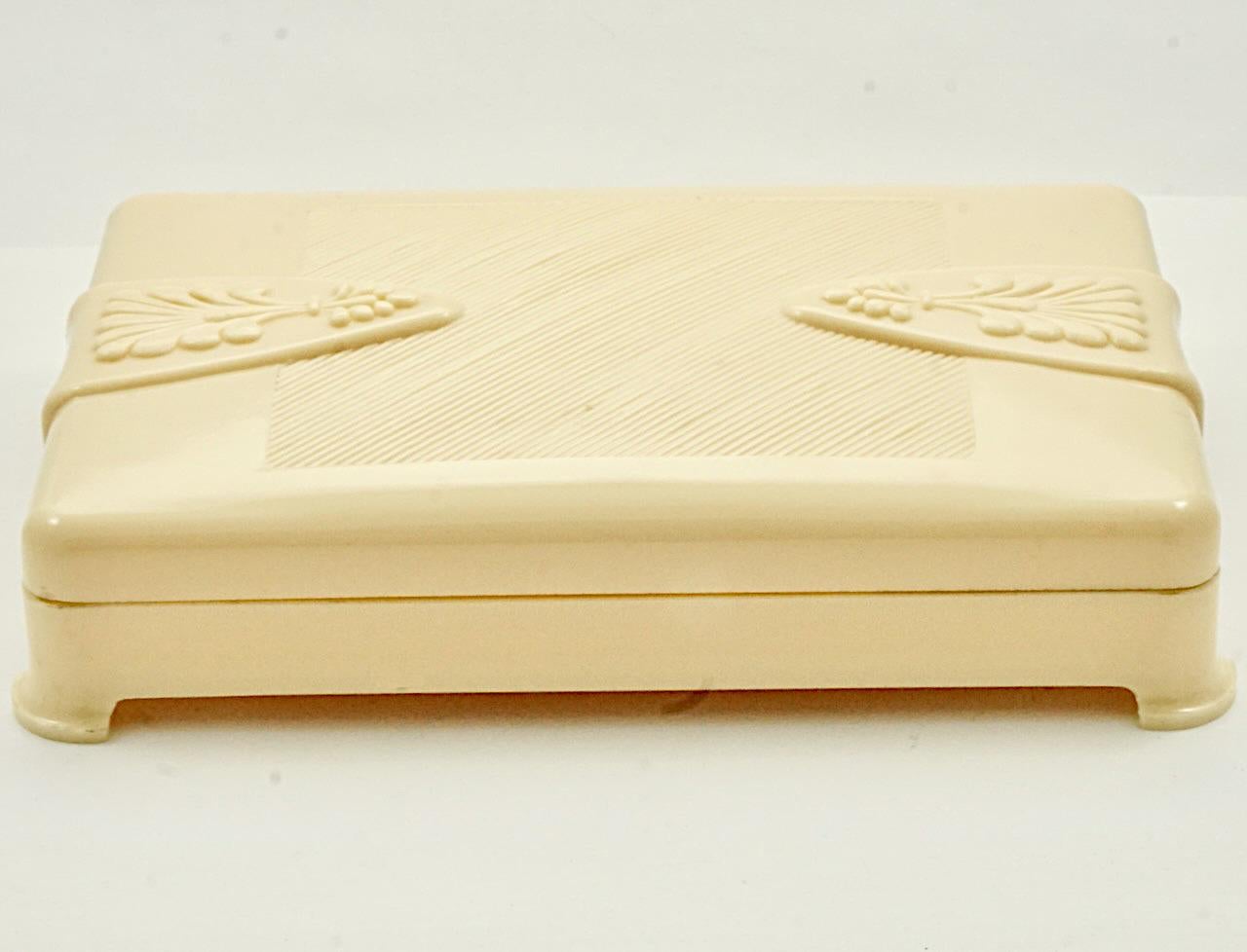 Belle boîte Art Déco en celluloïd crème. Longueur 14,3 cm / 5,6 pouces, largeur 9,6 cm / 3,77 pouces et profondeur 2,7 cm / 1 pouce. Le couvercle est orné d'un joli motif en relief. La boîte est en très bon état. Il y a une fissure au dos.

Cette