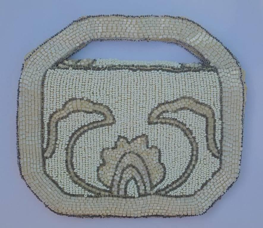 Art Deco bag featuring neutral colours of creamy white and shimmering ecru beads, with a brown bead edge. 16cm, 6.3 inches, by 11.3cm, 4.45 inches, not including the handle.
The bag closes with a popper. The lining is in good condition and has a