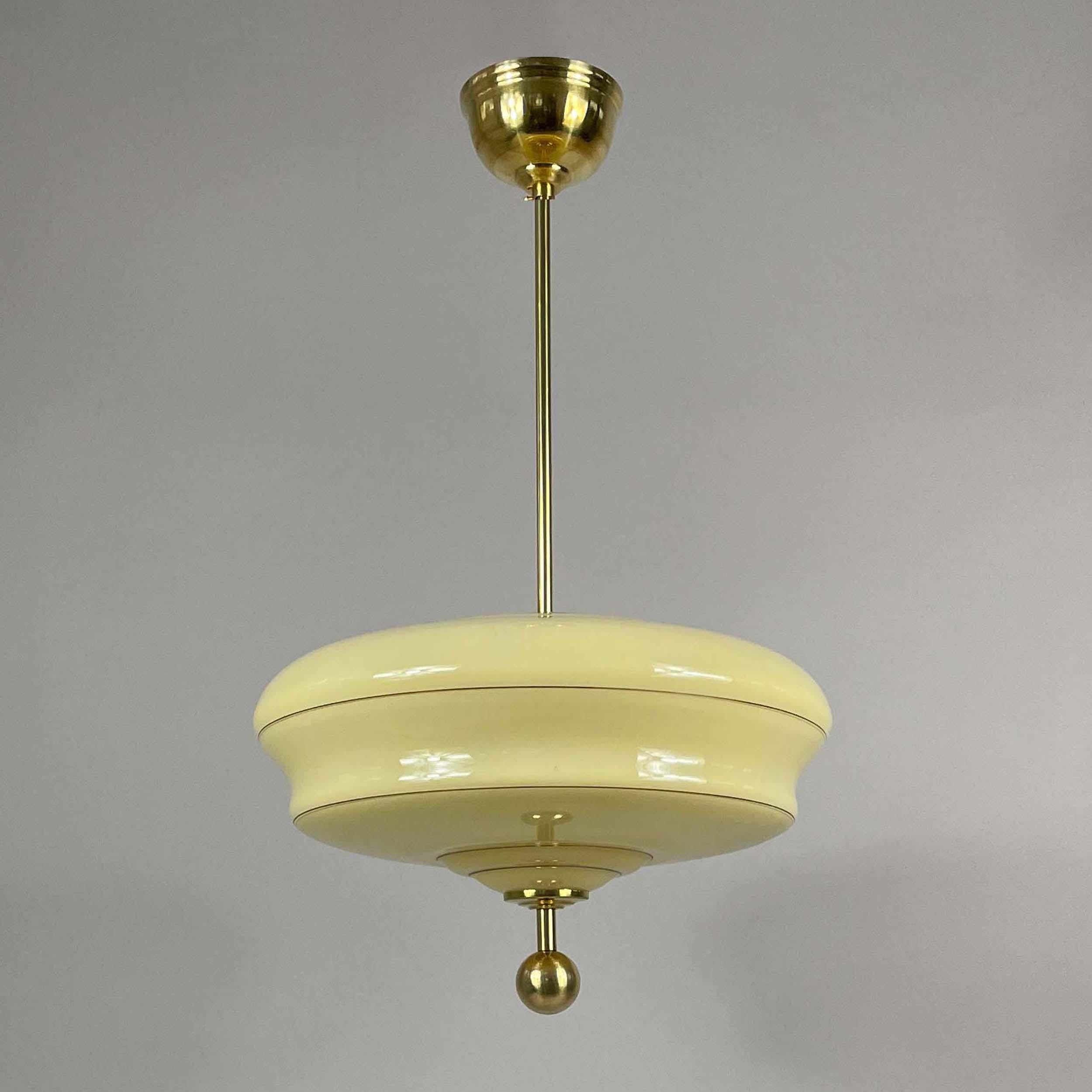 This elegant pendant was manufactured and designed in Sweden in the late 1940s. 

The light features a cream colored opaline lamp shade with gold plated decor and brass hardware giving it a luxurious and timeless appearance. It is a fine example of