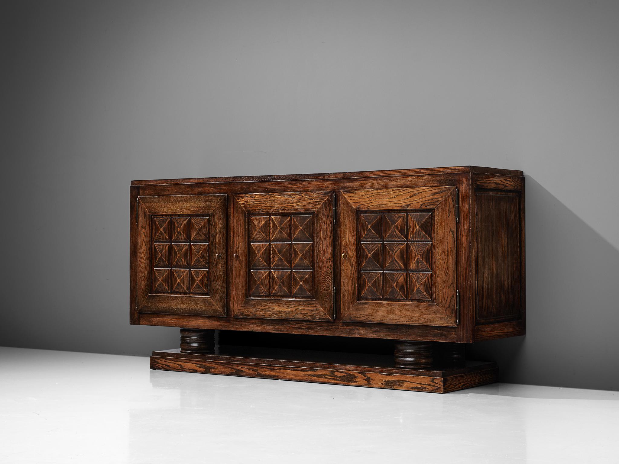 Gaston Poisson, credenza, stained oak, France, 1930s.

Sturdy sideboard in oak with graphical door panels. The sideboard is equipped with several shelves and one drawer which provide plenty of storage space. The door panels and base details show the