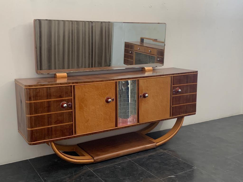Sideboard with arched base in maple and rosewood. Center carries a crescent-shaped niche trimmed in mirror mosaic. Gorgeous burgundy and chrome knobs and flasks. On the rosewood top is a mirror that rests on two maple plinths. Dimensions: Sideboard