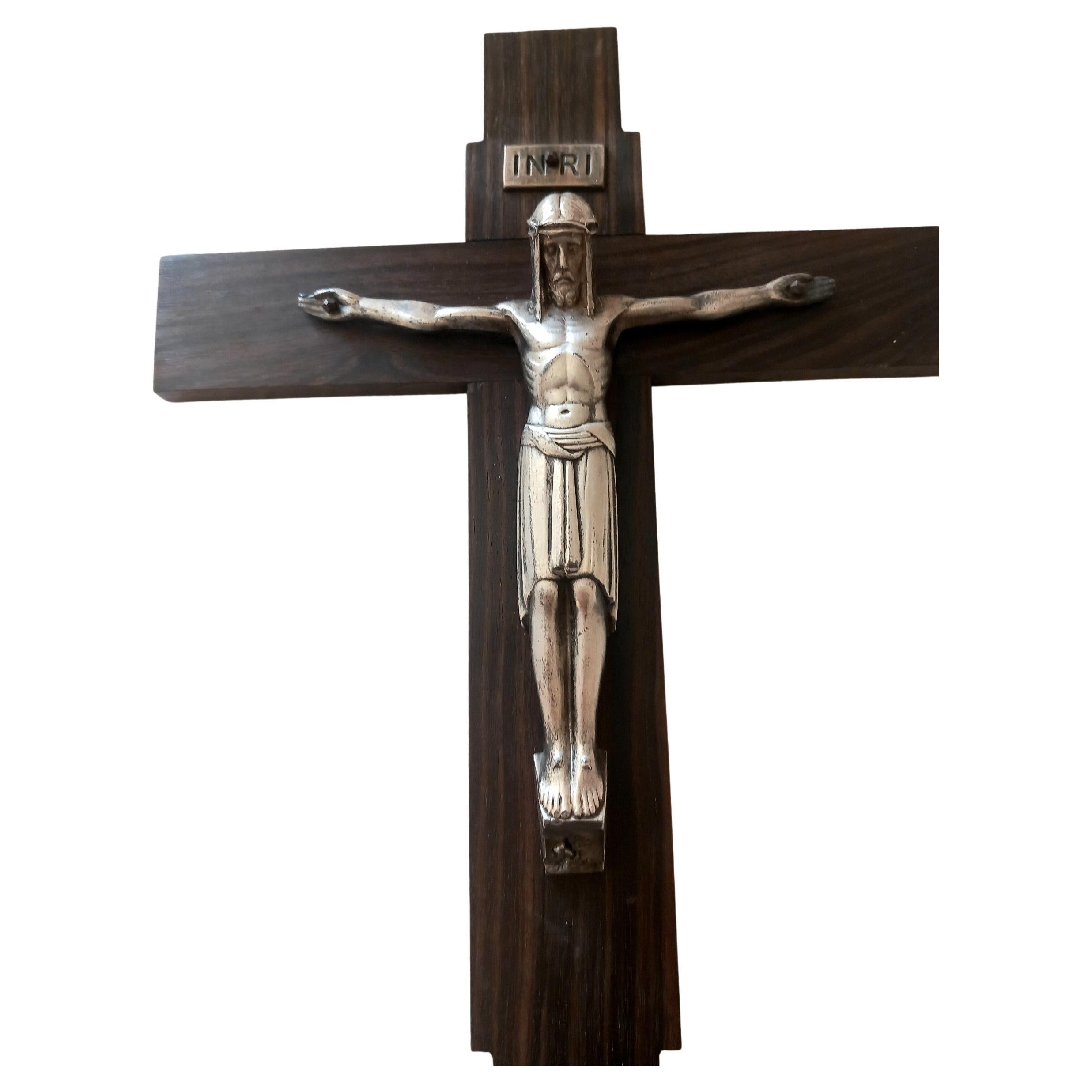 Crucifix Art Déco pour suspension murale, en métal palettisé sur croix en bois d'ébène africain ou coromandel.

  La figure du Christ a une silhouette précieuse et parfaite, façonnée dans le plus pur style Art Déco et la croix a une forme linéaire,