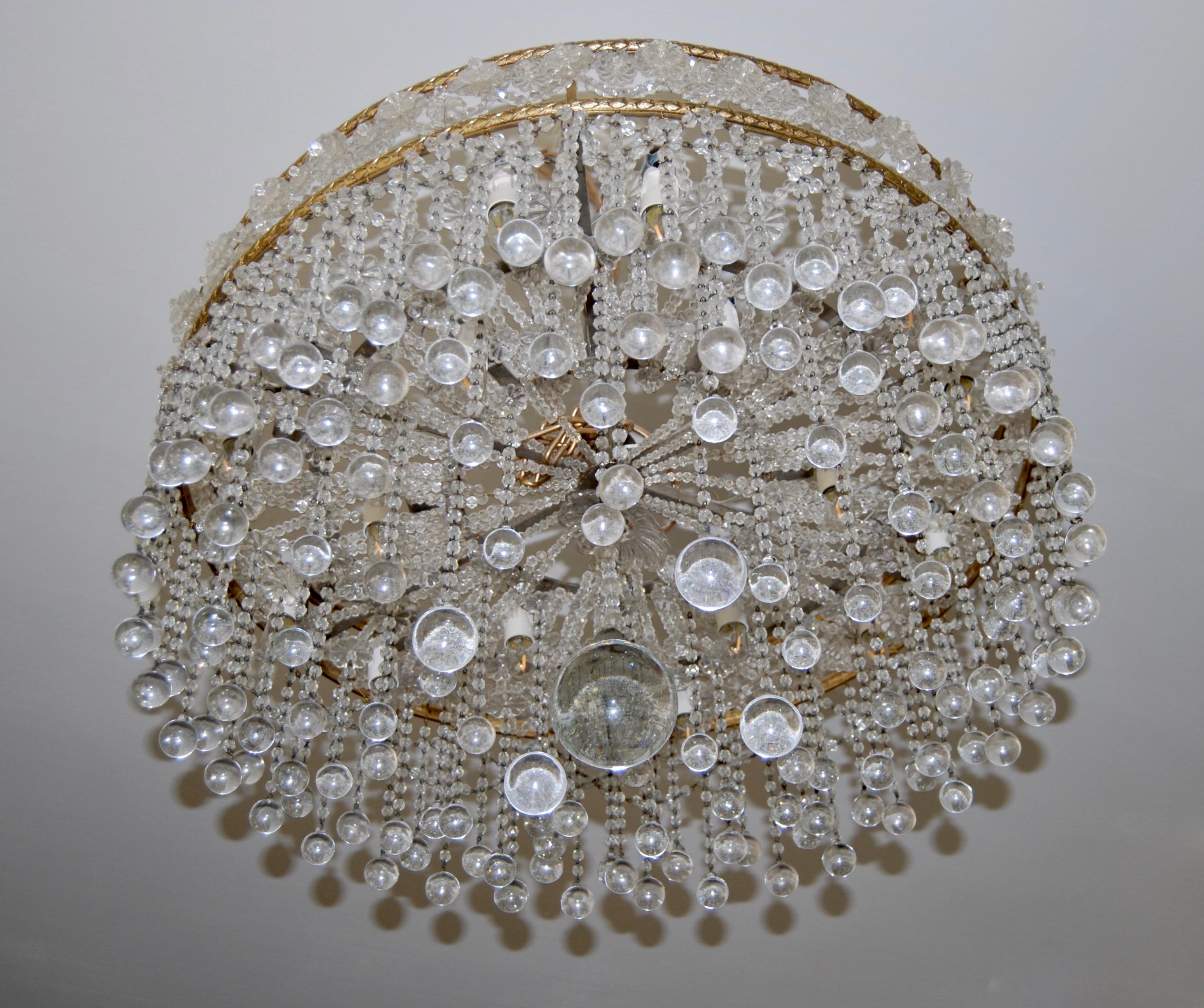 This spectacular chandelier has one large crystal ball as its centrepiece surrounded by 4 slightly smaller balls, then a series of others, smaller again, continue out to the edge
Crystal beaded chains hold them from two gilt bronze rings which are