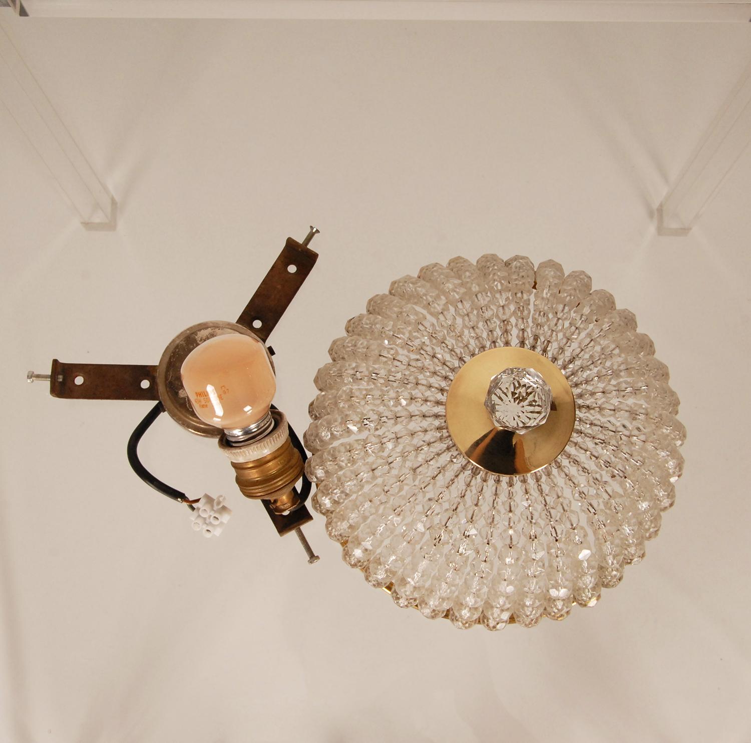 Art deco crystal and gold gilt brass flush mount ceiling fixture.
Crystal strands that converge into a rosette with cut crystal pendant finial in the gilt brass base
The crystal strands are original and woven on thick brass wires. 
Small flush mount