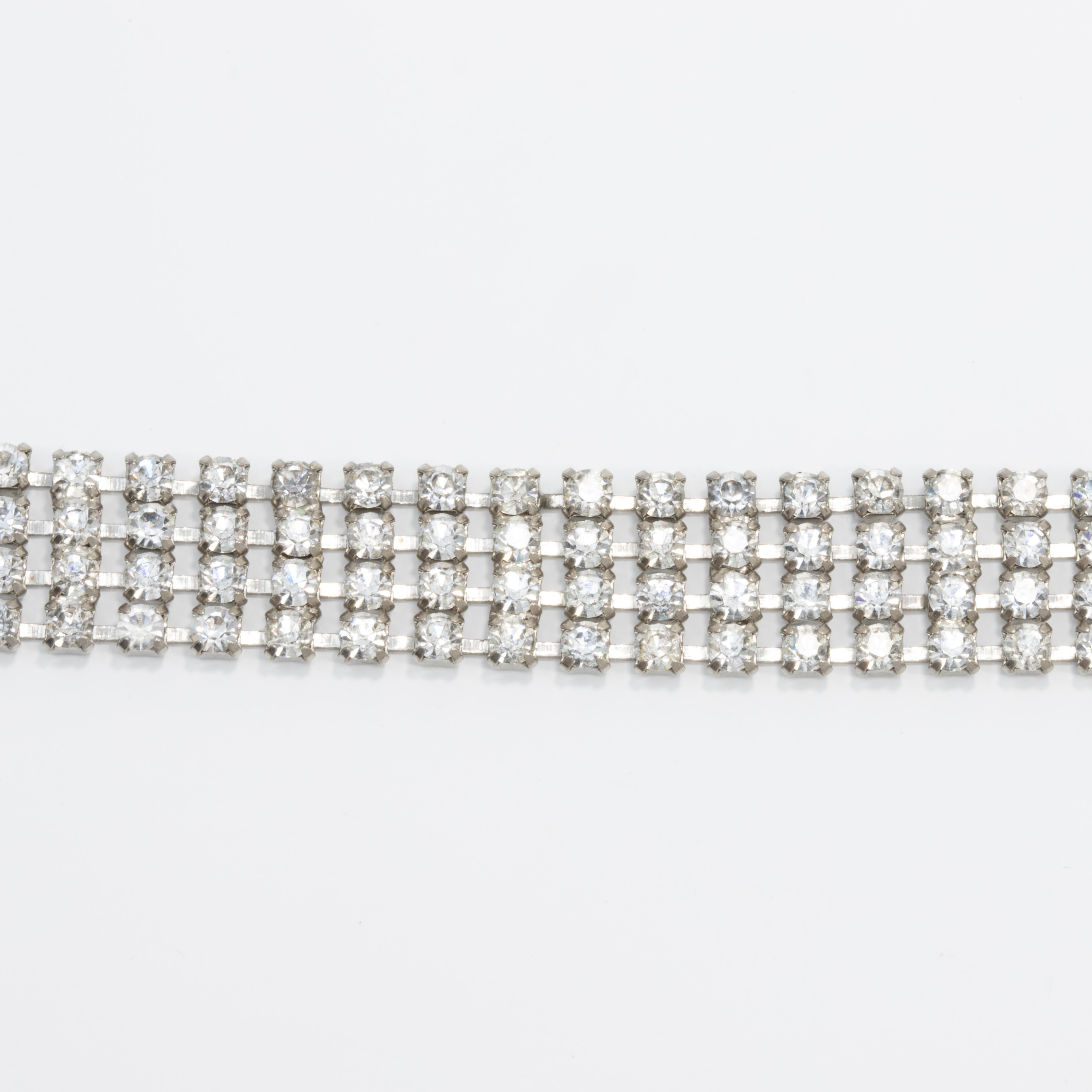 Early-1900s Art Deco bracelet featuring four rows of linked crystals, fastened with a foldover clasp.

Silver-tone.