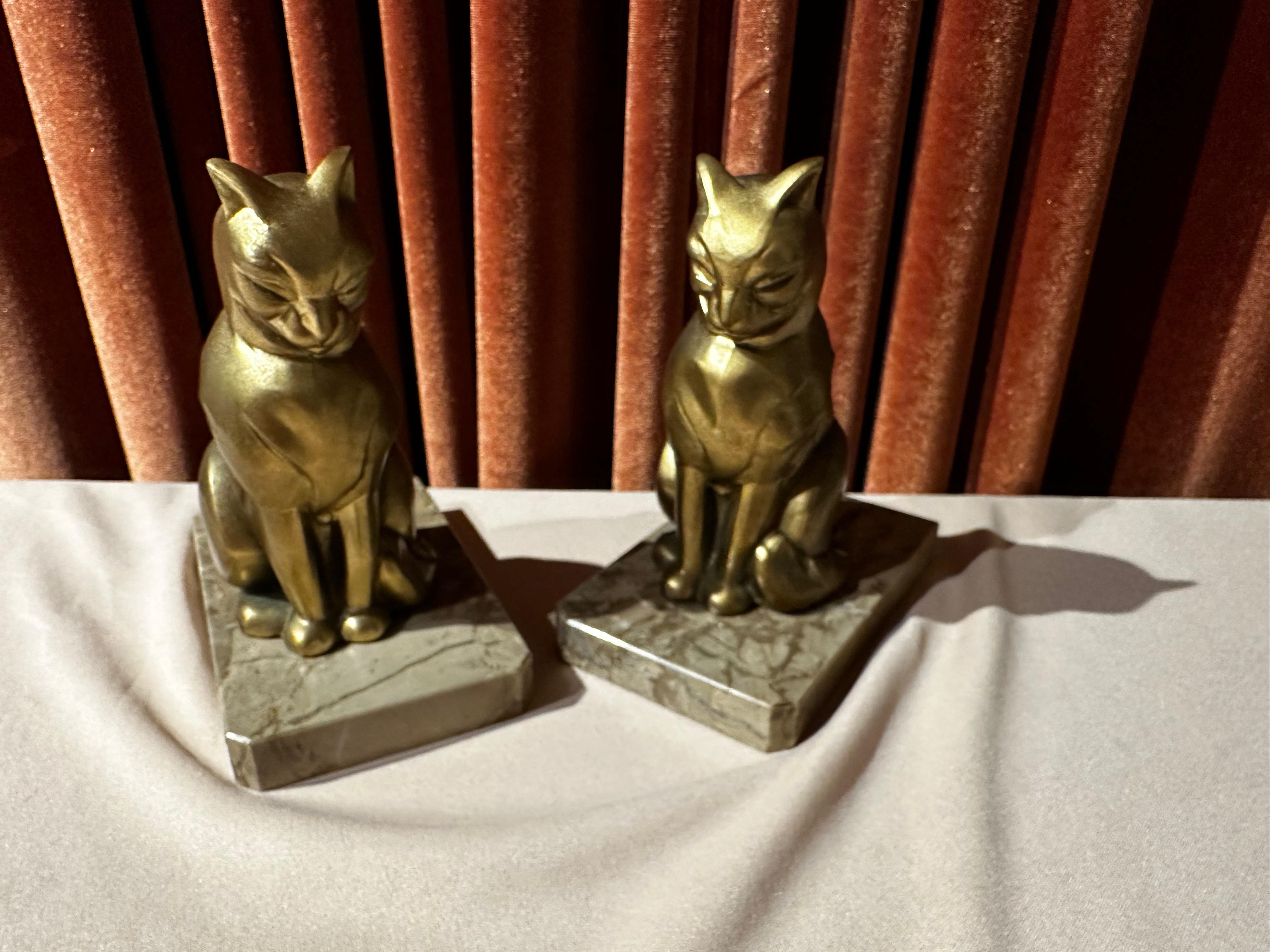 Art Deco cubist-style cat bookends by Franjou. These cat bookends are both signed Franjou, made in France, and dated between 1920-1949. These modern-style cats are made of gold patinated metal and have large expressive faces in a classic sitting
