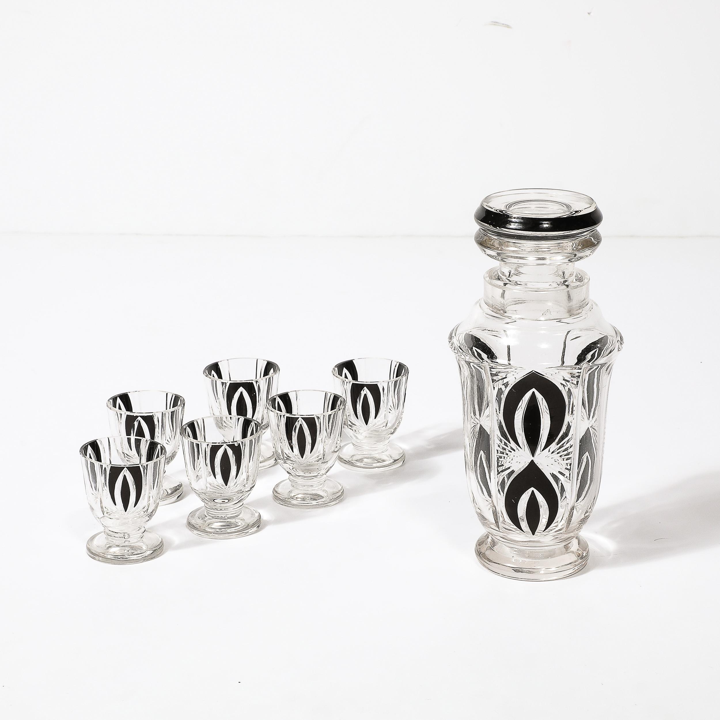 This striking Art Deco Decanter & Glass Set in Cubist Cut Crystal W/ Black Geometric Detailing originates from Czechoslovakia, Circa 1930. The set is rendered in a transparent cut crystal with geometric linear grooves and crescent shaped black