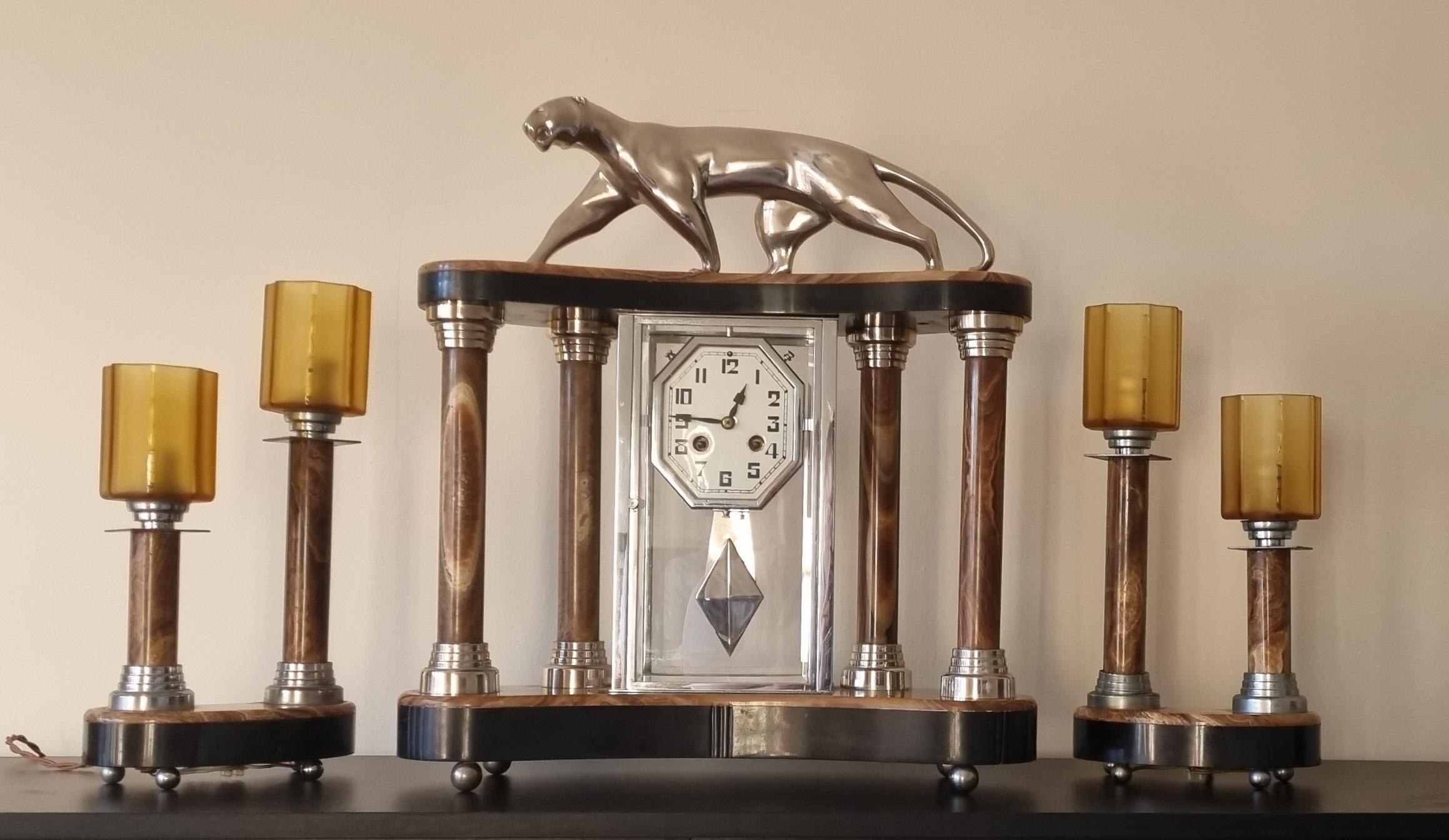 An iconic Art Deco clock by the renowned artist of Art Deco period, Michel Decoux. This exceptional piece boasts a highly decorative clock case, expertly crafted from rich marble and onyx, supported by sleek pillars with chromed motifs. At the top