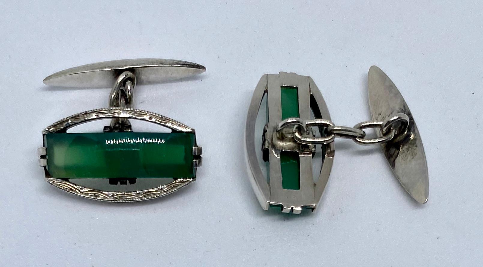 A pair of antique Art Deco cufflinks in sterling silver featuring bright green chrysoprase stones.

The tonneau-shaped cufflinks show exemplary Art Deco lines and details, along with a wonderful pop of color from the luminous green chrysoprase.