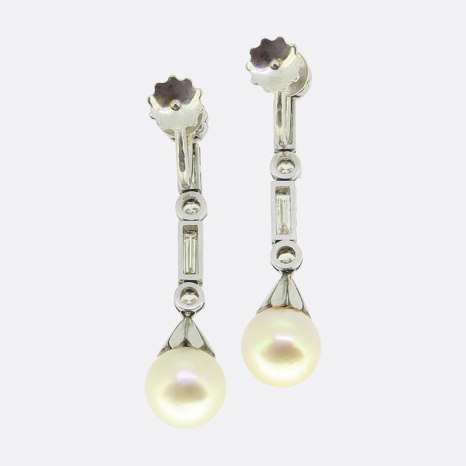 Nous avons ici une splendide paire de boucles d'oreilles en forme de goutte d'eau présentant un mélange harmonieux de perles et de diamants. Réalisées en platine circa. 1940, chaque boucle d'oreille présente une perle de culture blanche arrondie,