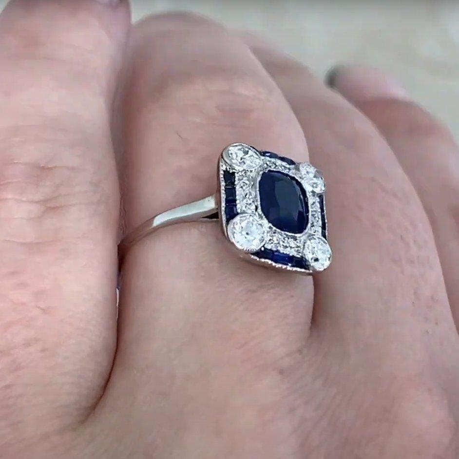 Cette exquise bague Art déco, fabriquée vers 1925, est ornée en son centre d'un saphir de taille coussin, pesant environ 1 carat. La riche teinte bleue du saphir est parfaitement complétée par un double halo sophistiqué - une couche de diamants