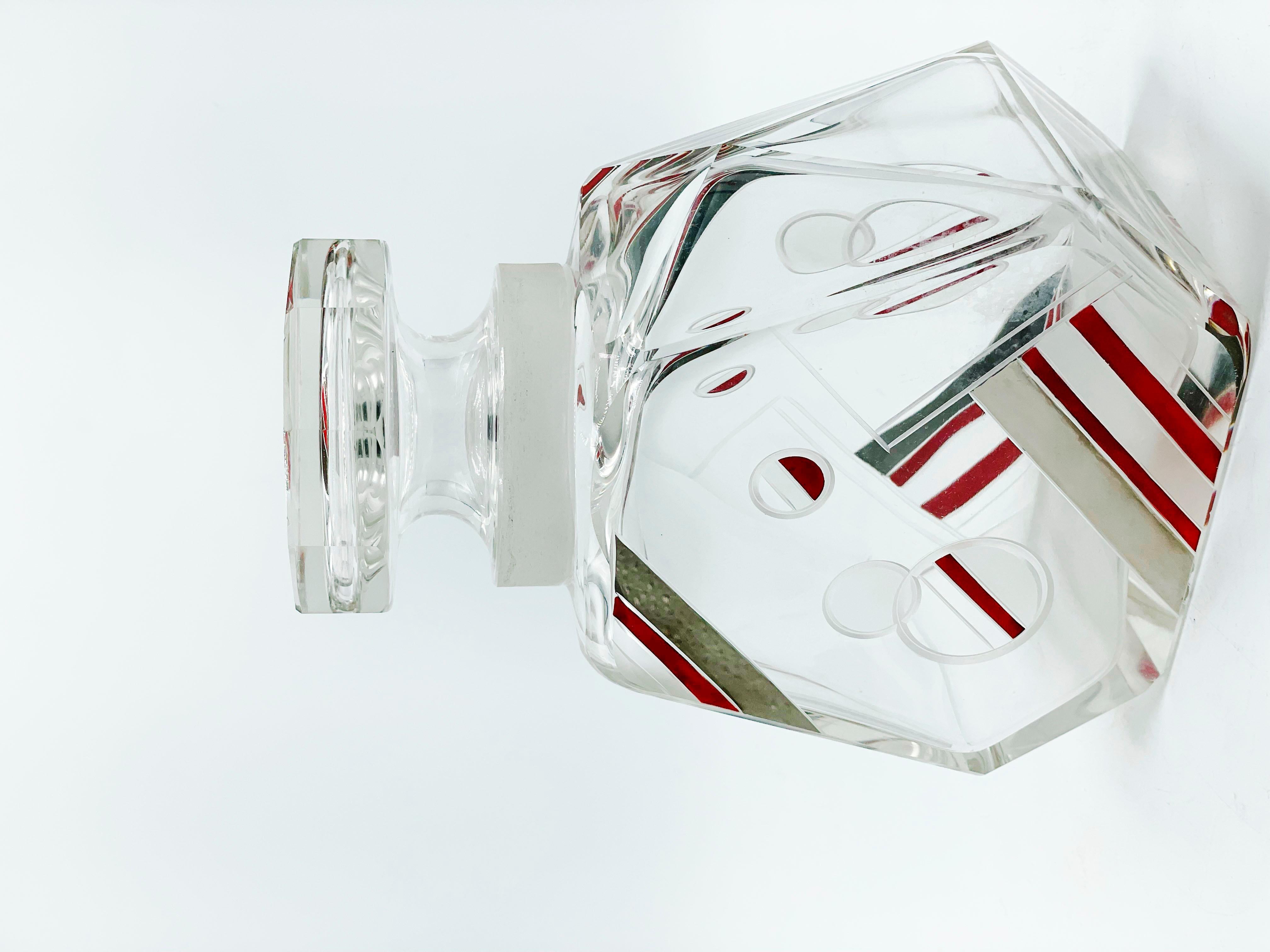 Art Deco Cut Crystal Decanter by Karl Palda
This piece, both the shape design and the crystal pattern design are made of geometric shapes, endowed with red and silver circles and lines. The cap also consists of the same design as the main