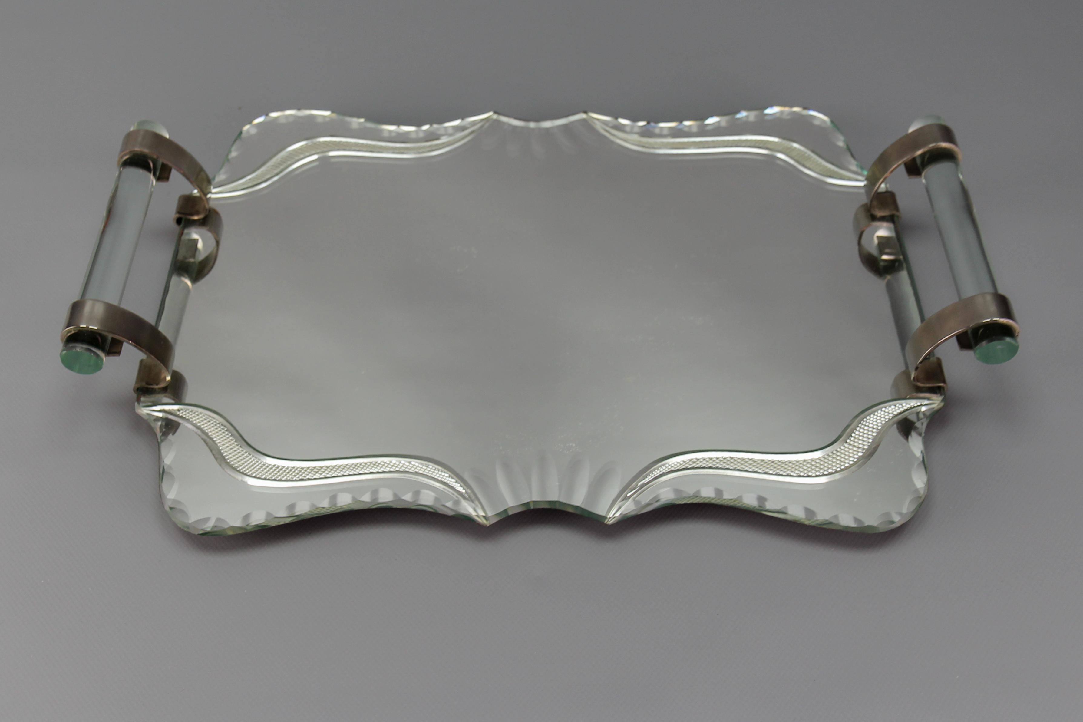 Bandeja de servir Art Decó tallada en espejo, cristal y cromo, Francia, años 30.
Una elegante y clásica bandeja Art Decó para servir o para el bar, fabricada con una base de espejo tallado con detalles biselados. Las asas son de cristal grueso y