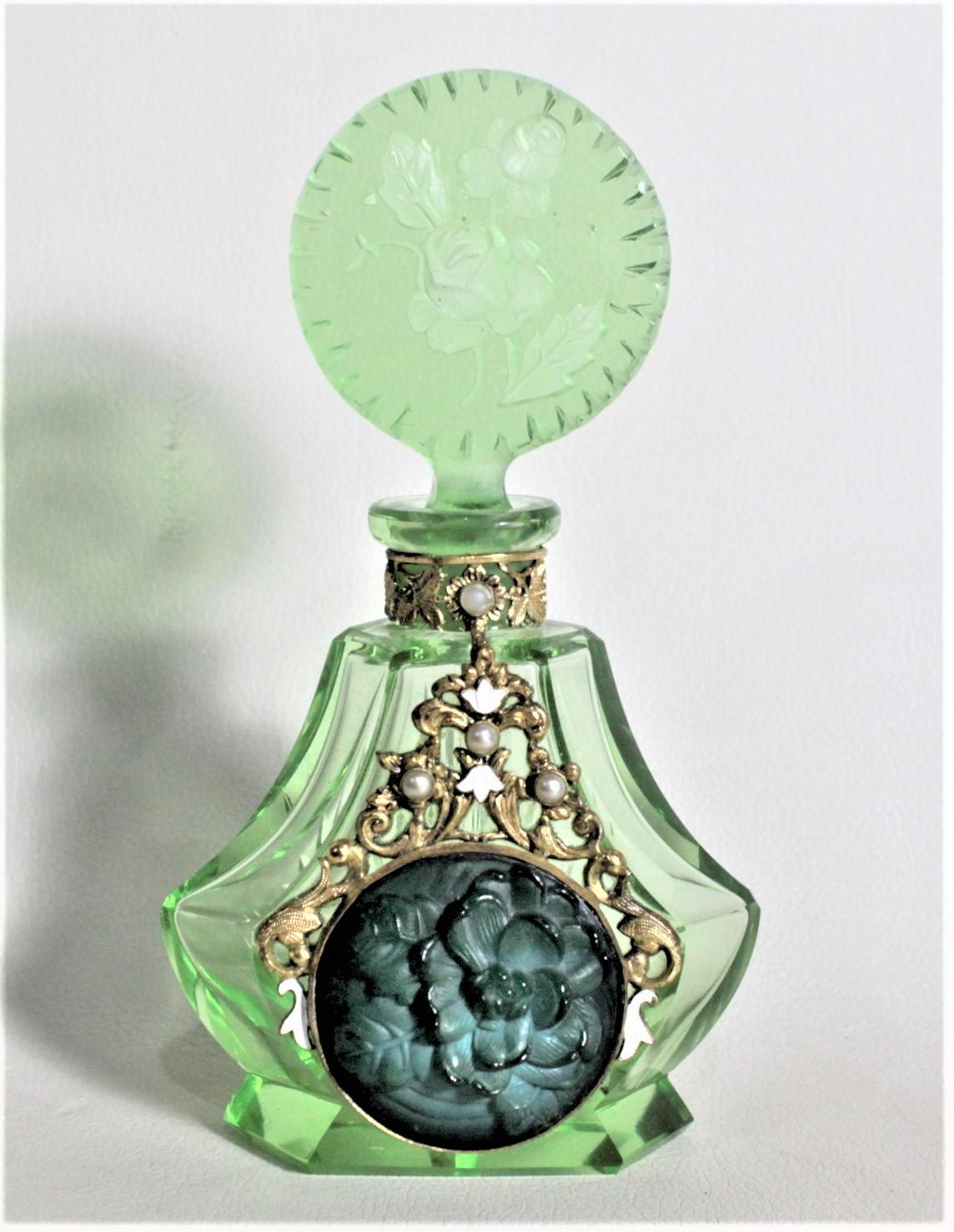 This Art Deco perfume or scent bottle is unsigned, so the artist cannot be identified, but was made in Bohemia in approximately 1935. The glass is a deep green with deep faceted sides and etched and cut top. The bottle features an ornate gold toned