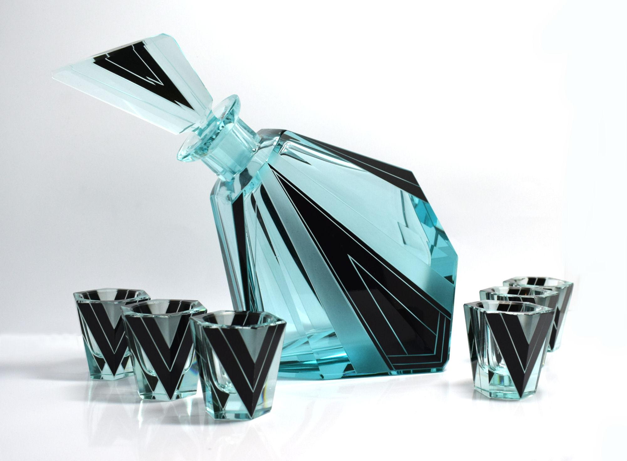 Wonderfully quirky and stylish Glass decanter set sourced in Prague. Geometric enamelling decorate the attractive turquoise crystal, stunning shape and cut, small shot glasses. Comprises decanter and stopper with six glasses. Condition is excellent