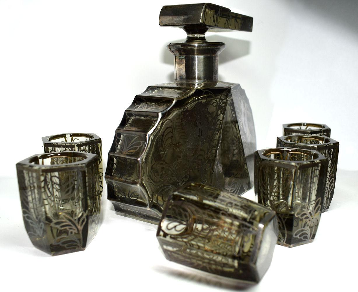 Very unusual and slightly wacky shaped 1930s Art Deco decanter set originating from Czechoslovakia. Comprises decanter, stopper and six glasses. Clear heavy cut-glass with floral silver overlay decoration with horses. The decanter is deceptively