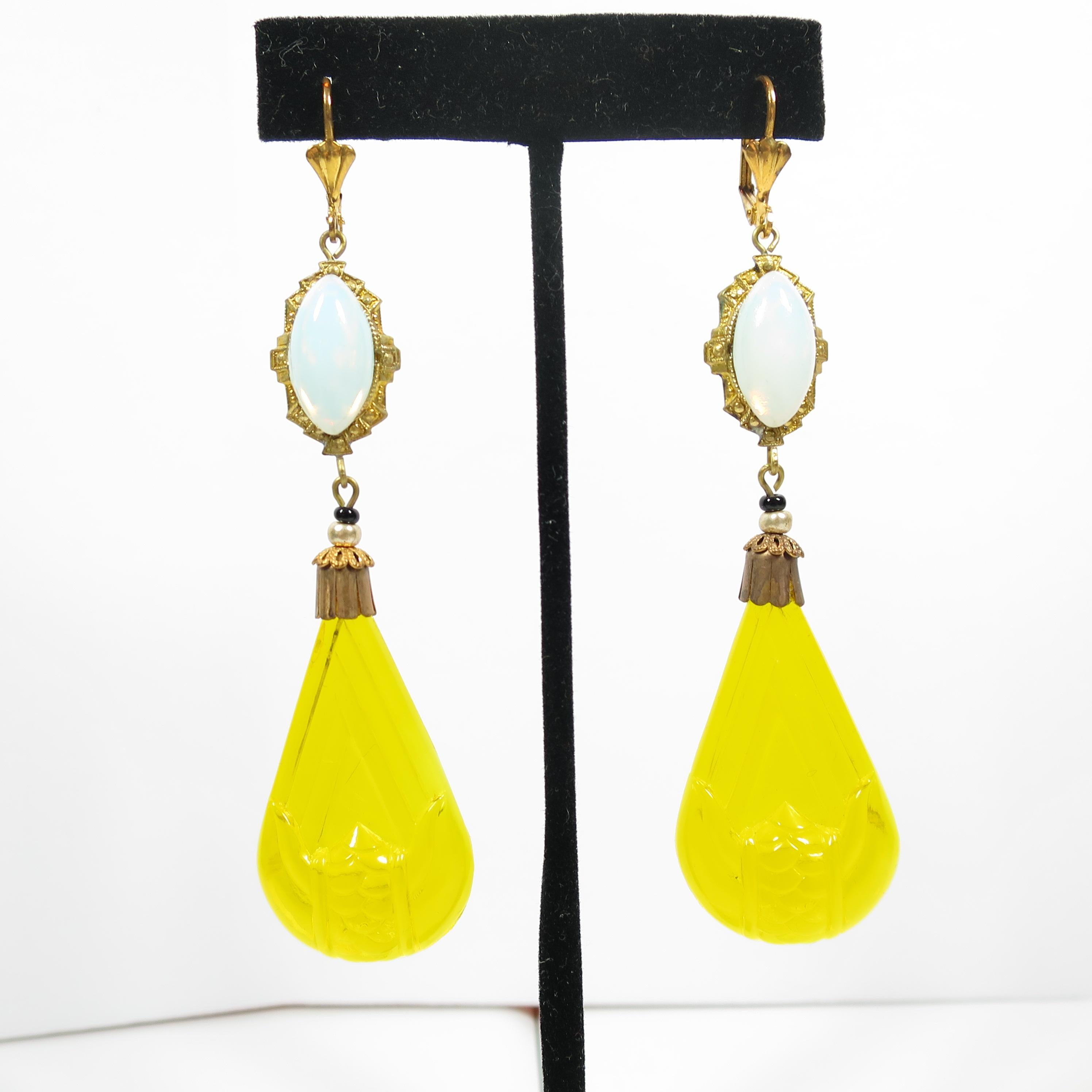Offered here is a pair of Art Deco Czech pierced lever-back opal & citrine carved glass dangle earrings from the 1920s. The hand-soldered top portion is a gold-washed oval platform with marquise cabochons of opal art glass surrounded by geometric