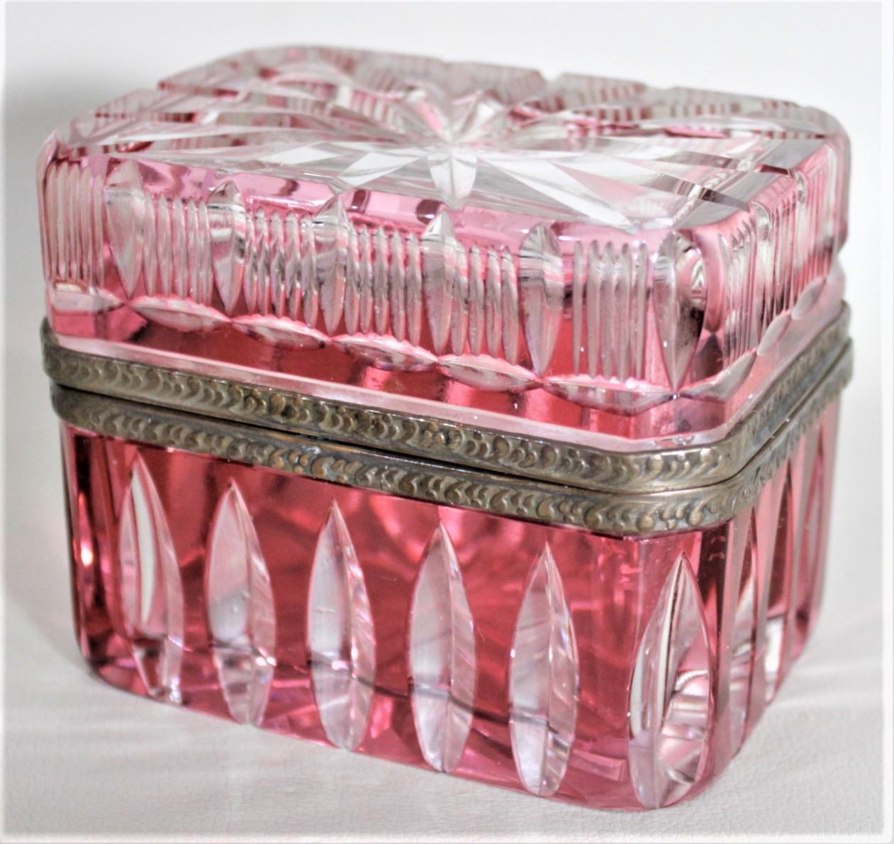This nicely executed glass jewelry casket or box was most likely made in Bohemia, now the Czech Republic in circa 1920. The top and bottom of the box are done with a ruby colored glass cased over clear glass which have been handcut to give the