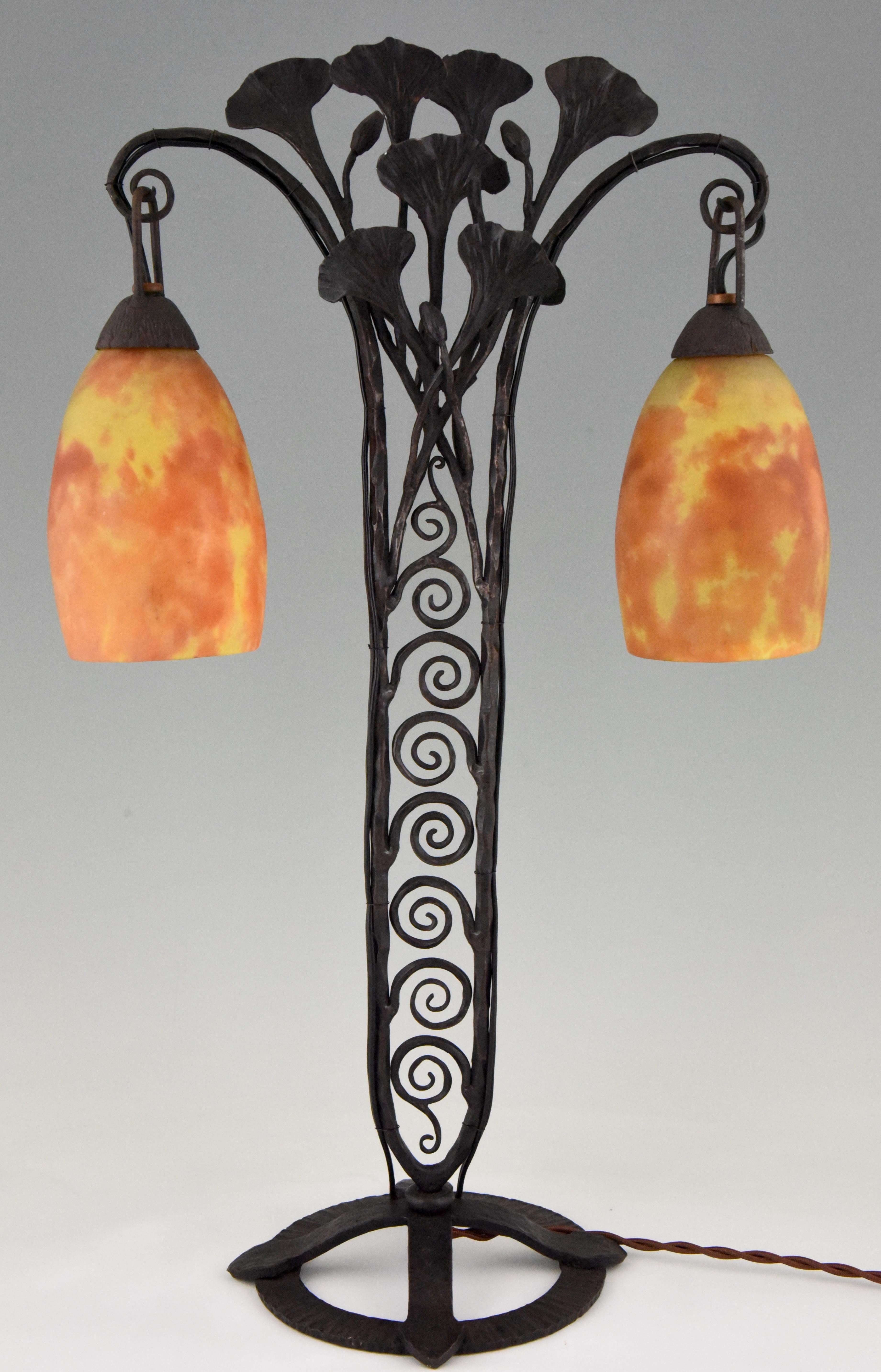 Beautiful Art Deco table lamp with two daum glass shades in orange and yellow tones. Signed on the glass. The base is in wrought iron and decorated with leaves, France, 1925.