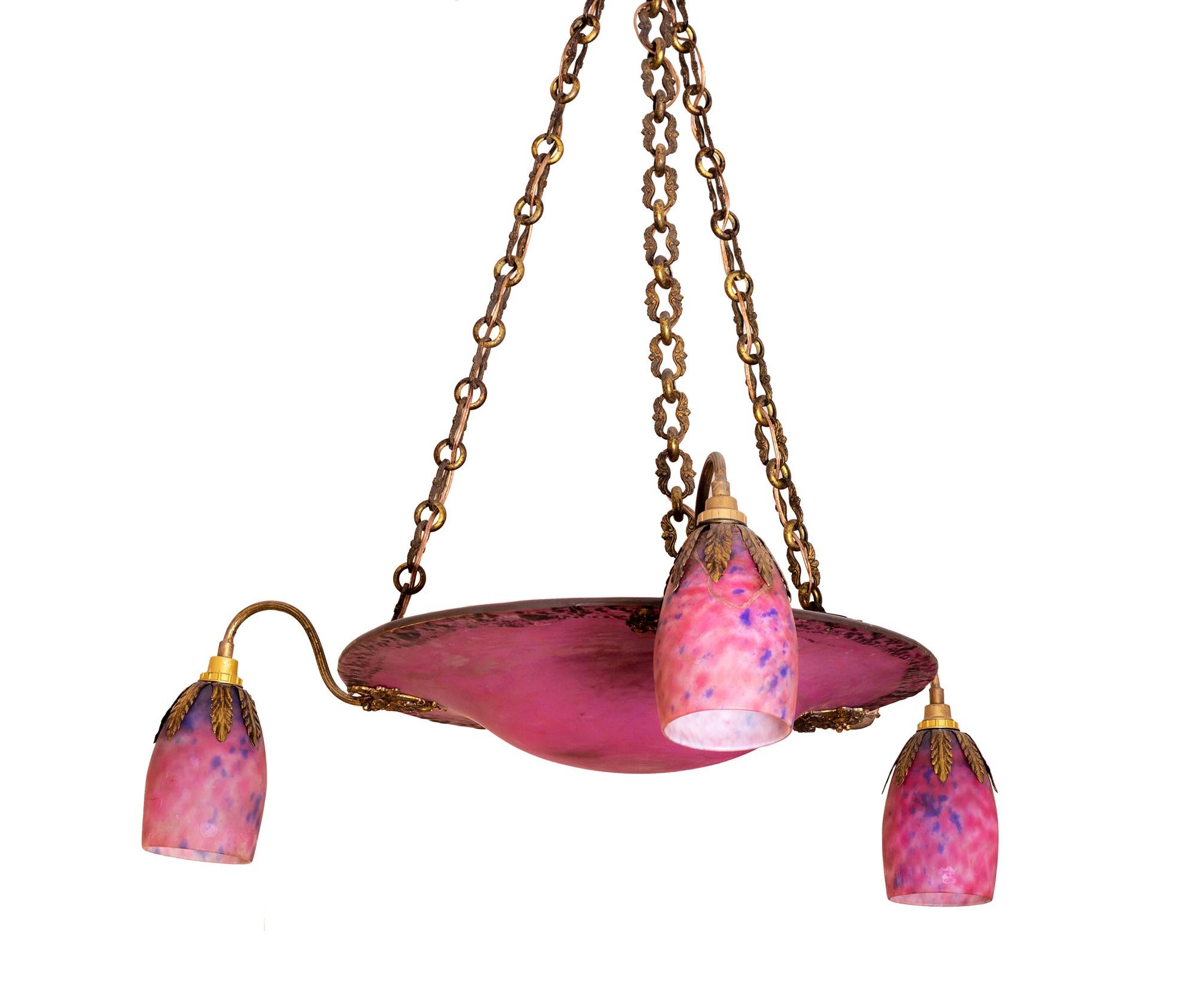 A stunning Daum Nancy Art Deco chandelier featuring three elegantly curved arms, a central glass bowl and four illuminants, all mounted in gilt brass. 

The chandelier is signed Daum Nancy and adorned with the Lorraine Cross, a hallmark of exquisite