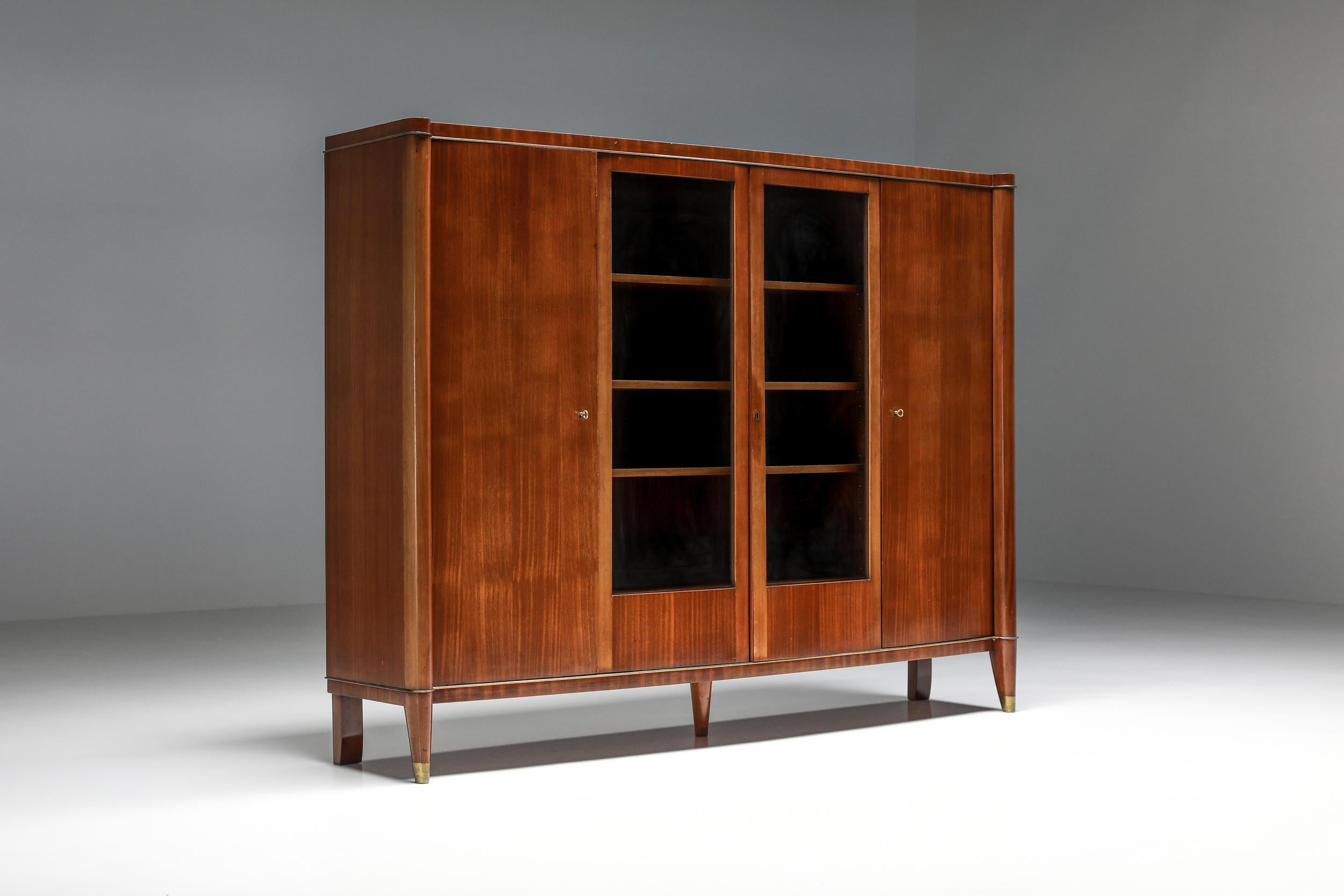 Exquisite 1920s Art Deco De Coene Voltaire bibliothèque or cabinet, a rare gem straight from the heart of France's design heritage. Crafted with a meticulous blend of wood, this stately piece features twelve generous shelves that beckon to showcase