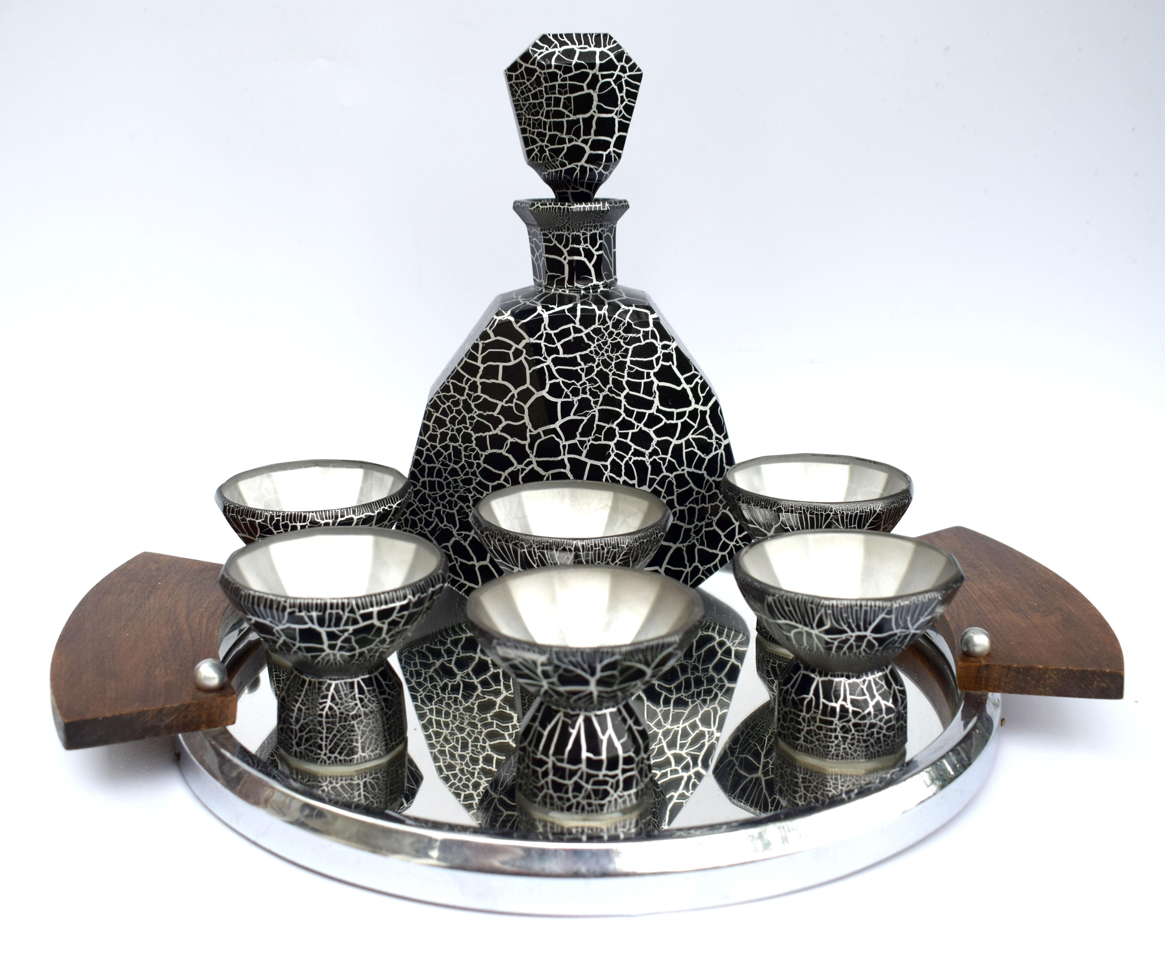 Superbly stylish Art Deco decanter set dating to the late 1920s-1930s made in the Czech Republic. This set features a large impressive decanter with stopper and six matching conical shaped glasses. The whole set is black enameled with silver overlay