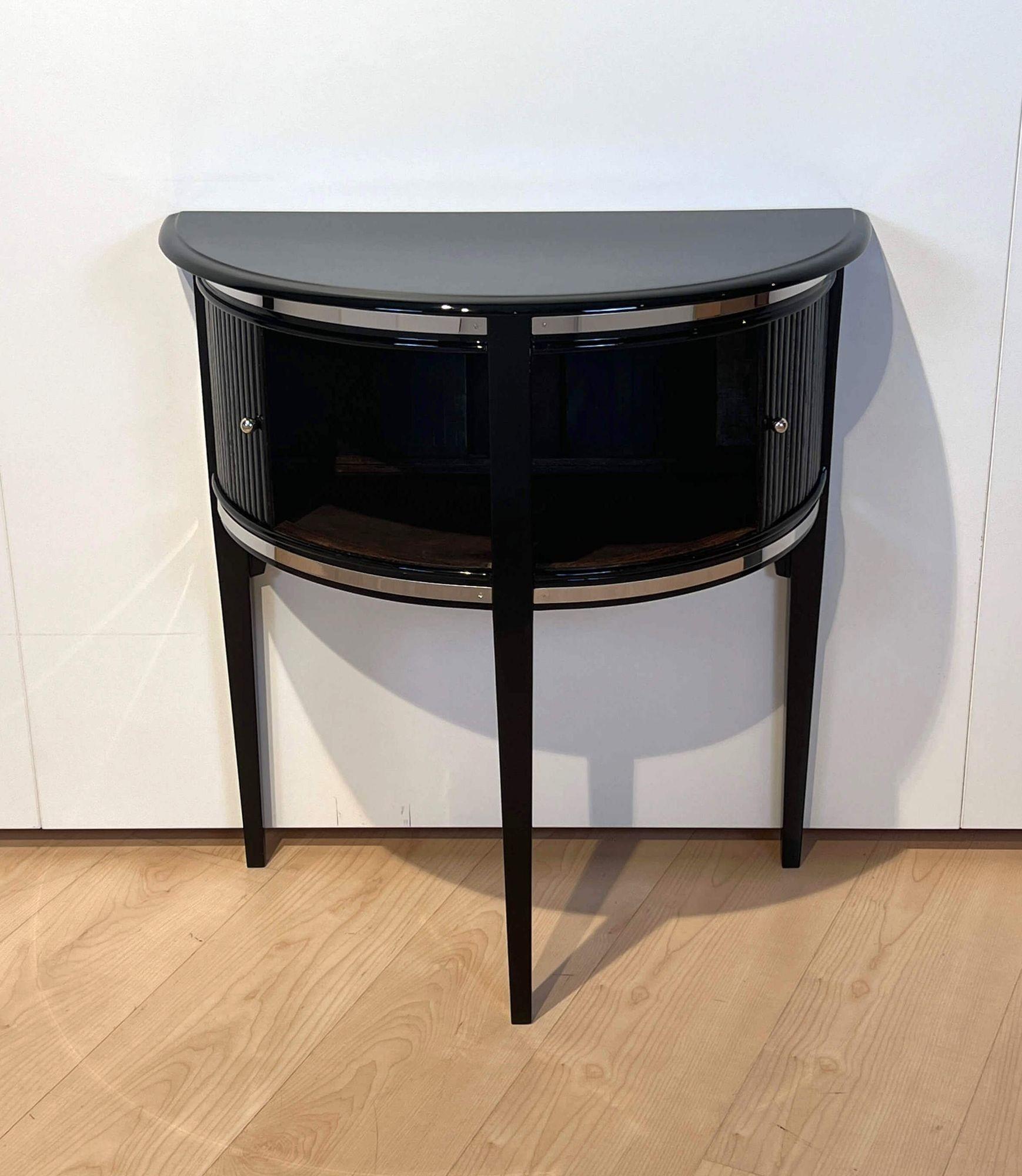 Oak, high gloss black lacquered and polished. Standing on three conical square legs.
Front with 2 sliding shutter doors (right side has been glued in the past and stucks a bit, but is working). Polished stainless steel trim.
 
Dimensions: H 72 cm
