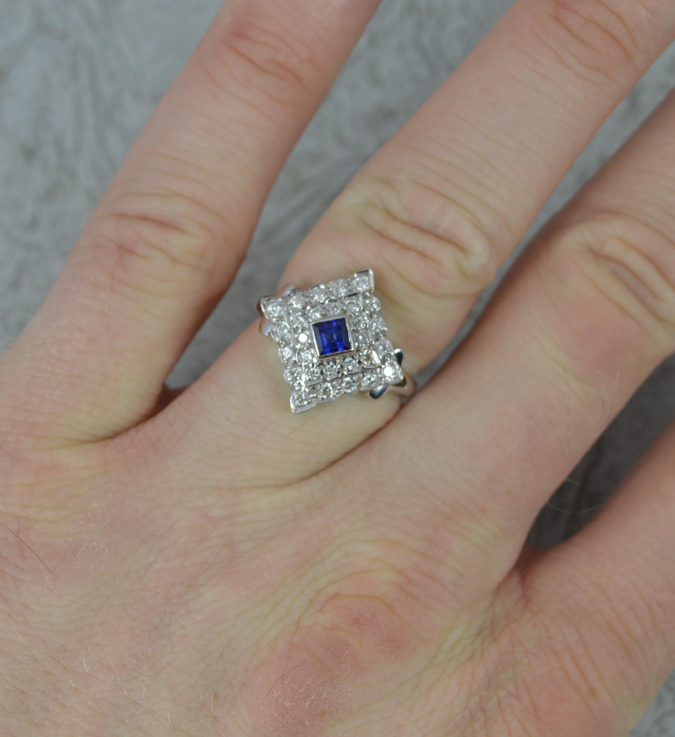 A striking contemporary Sapphire and Diamond cluster ring of art deco design.
Solid 18 carat white gold example throughout.
Designed with a princess cut blue sapphire to centre in full bezel setting. Surrounding is a double row of round cut